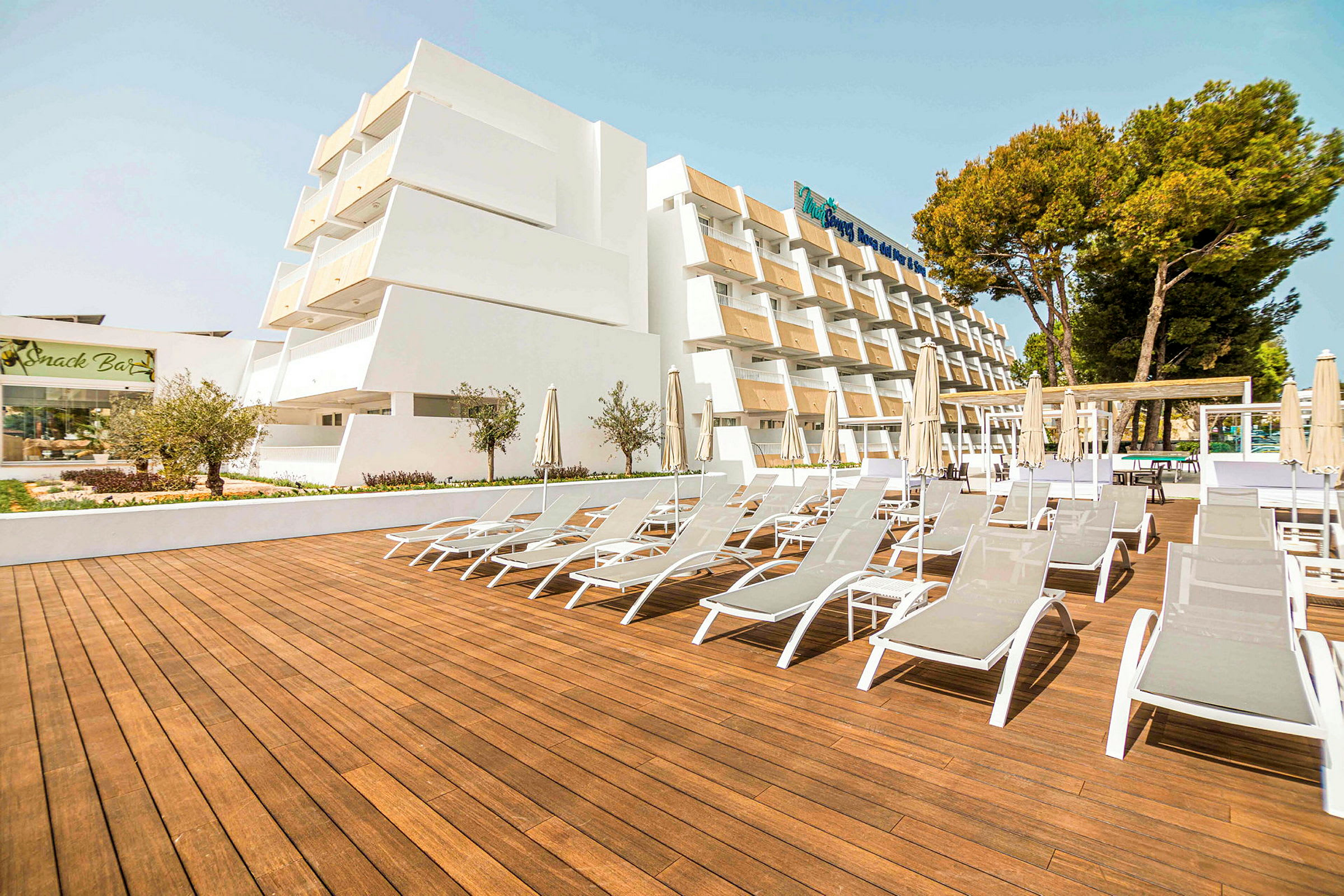 Bilde av et hotell med solsenger på en terrasse av tre. (AI-generert tekst)