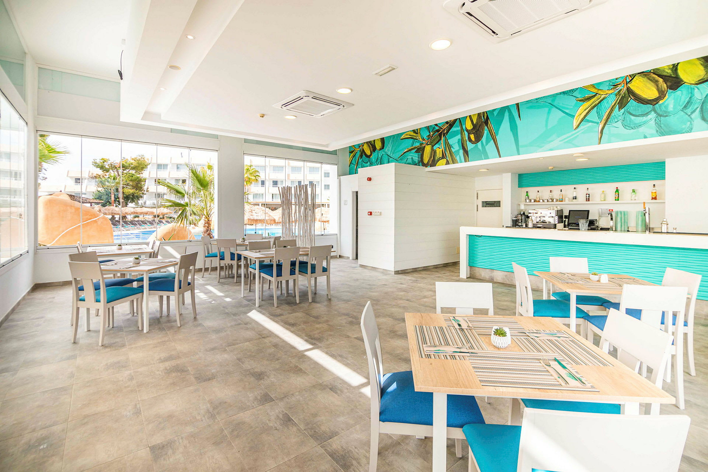 Lyse møbler i en moderne restaurant med blå detaljer og store vinduer. (AI-generert tekst)