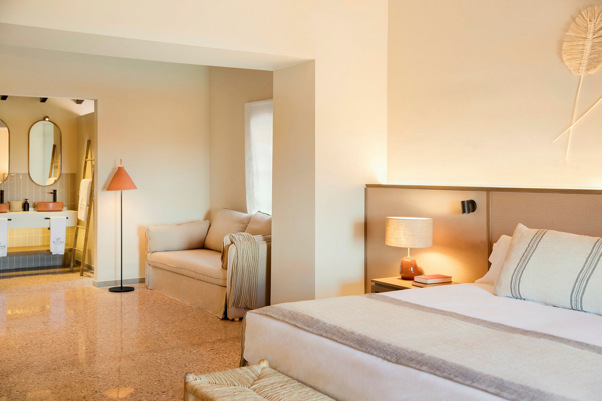 Et stilrent hotellrom med en seng, sofa og et åpent bad. (AI-generert tekst)
