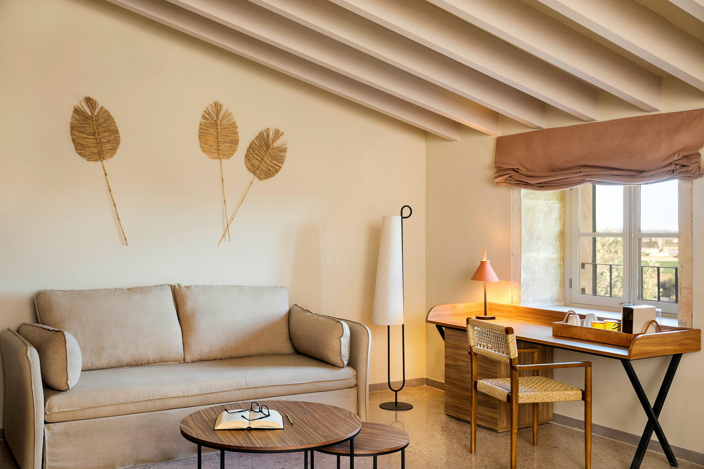 Et rom med en beige sofa, trebord og en skrivebordplass med vindu. (AI-generert tekst)