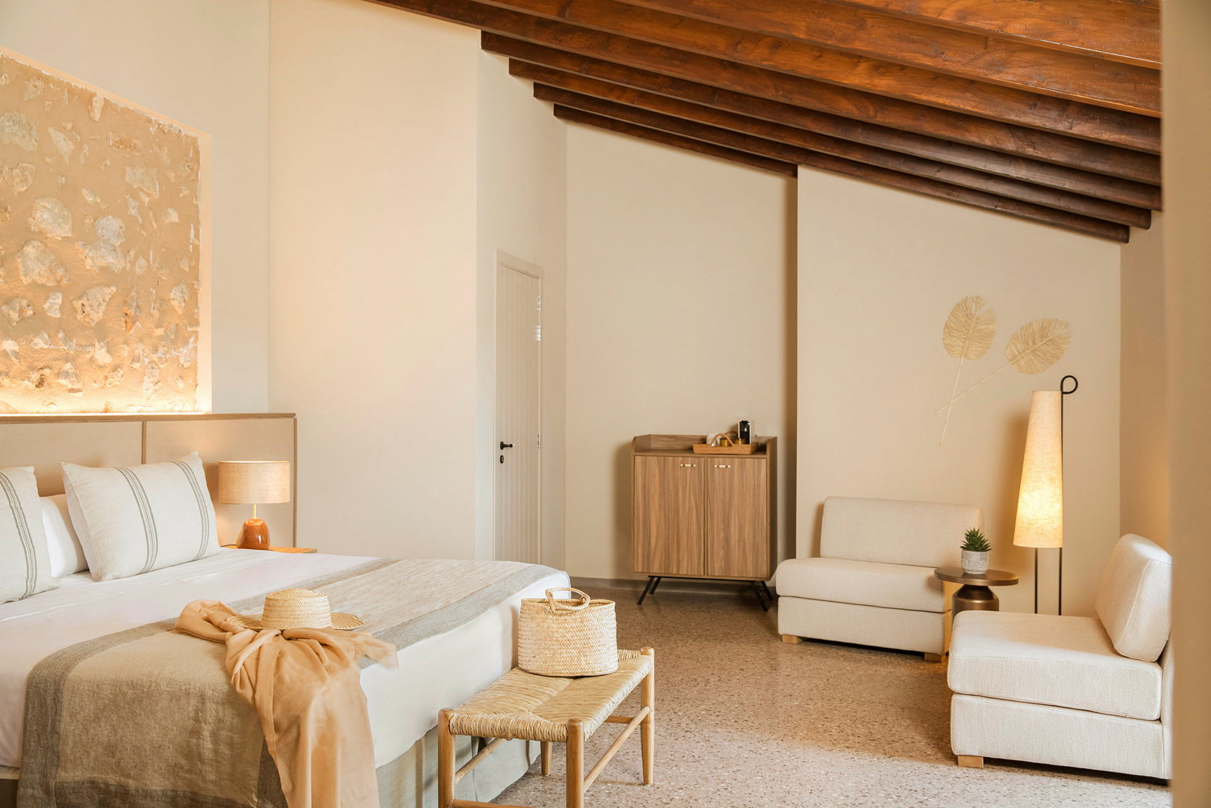 Et innredet hotellrom med en seng, sittemøbler og et skap. Rommet har en varm, moderne stil med beige og naturlige trematerialer. (AI-generert tekst)