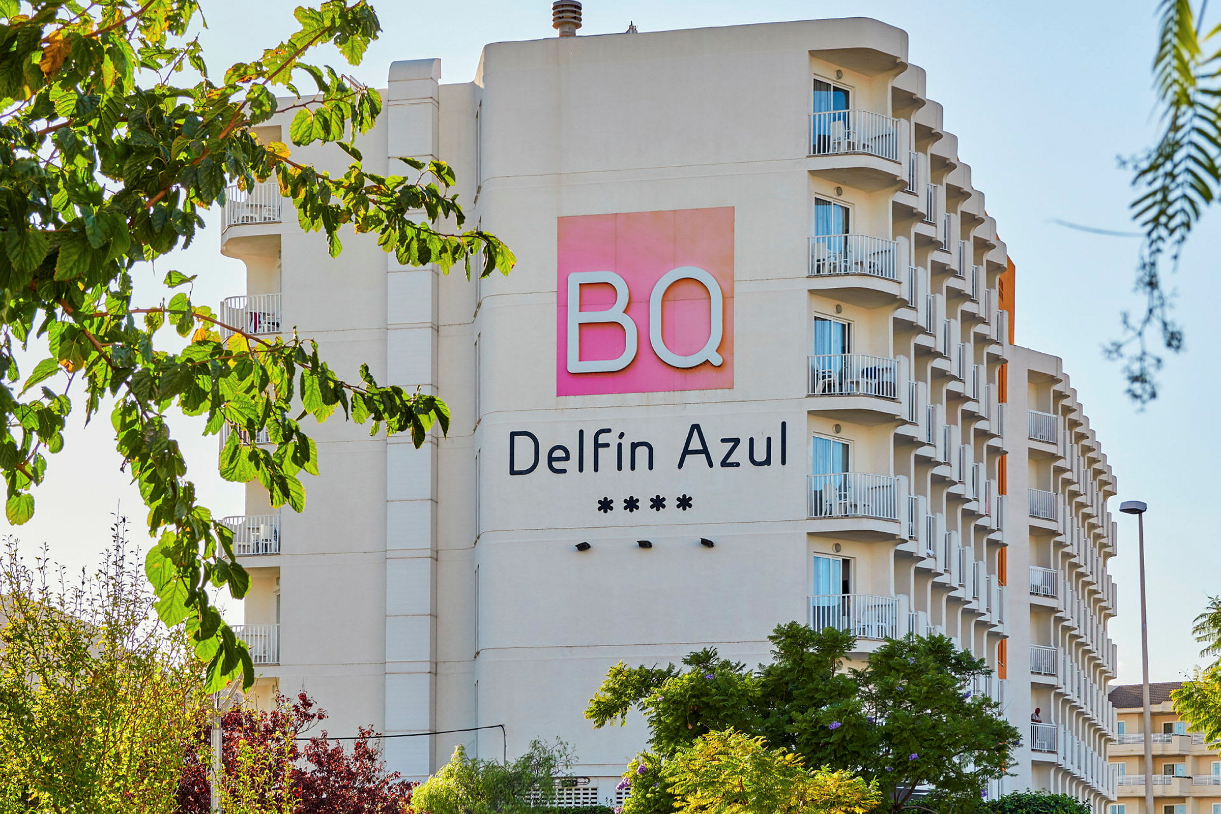 Hotellfasade med navnet BQ Delfin Azul og fire stjerner, omgitt av trær. (AI-generert tekst)
