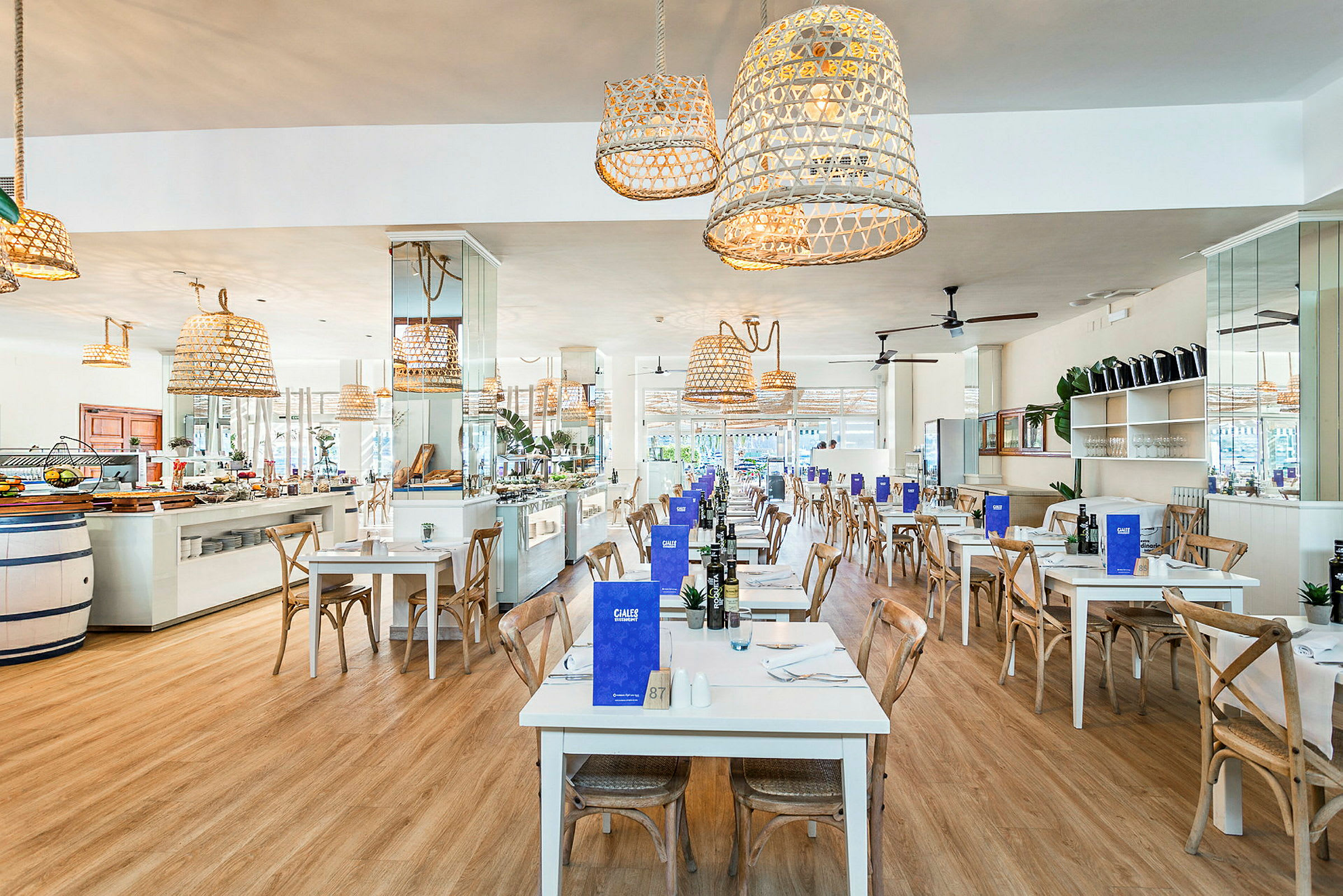 Restaurant med hvite bord og trestoler, dekorert med hengende flettede lamper. (AI-generert tekst)