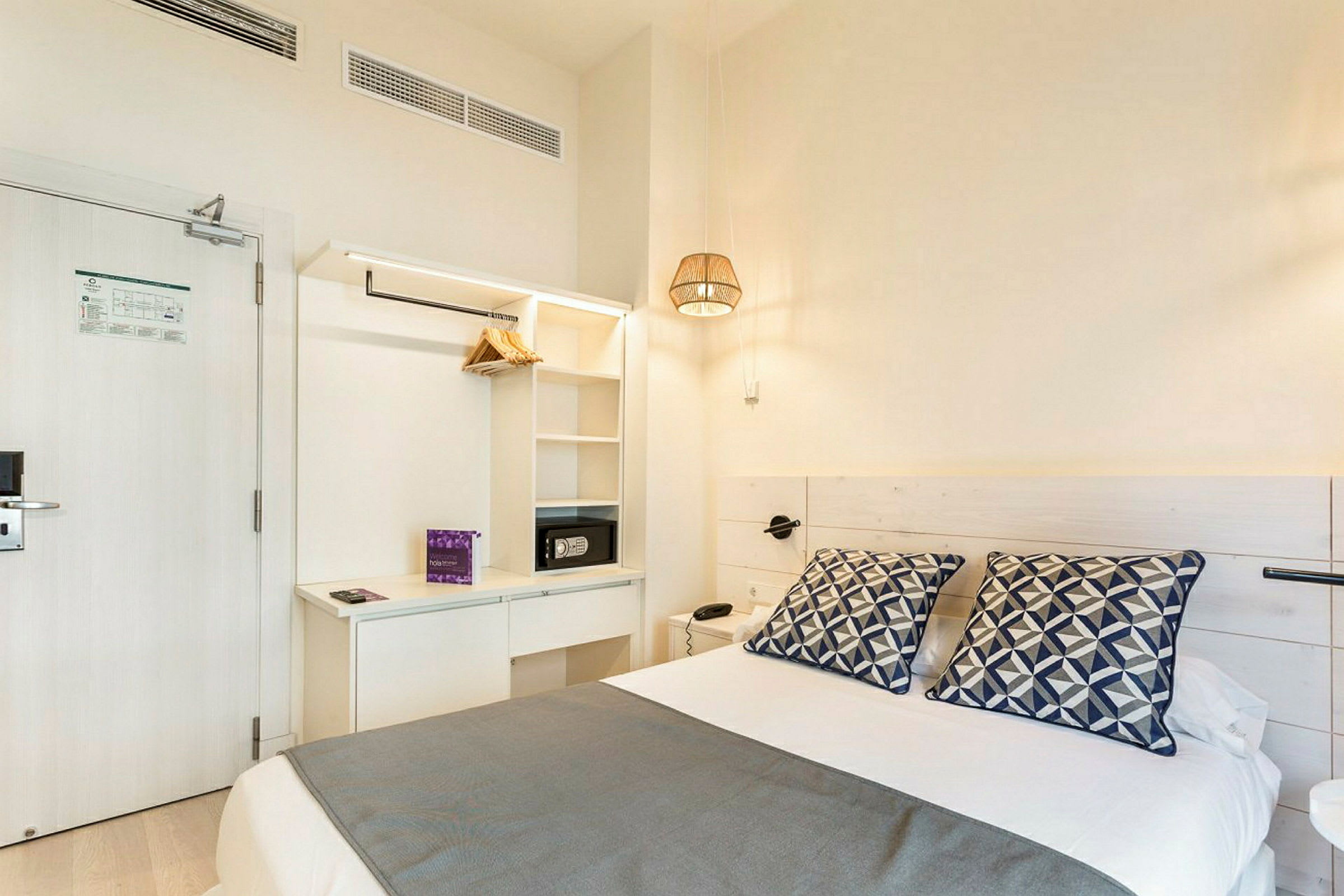Hotellrom med en seng, laken, pynteputer og oppbevaring. (AI-generert tekst)
