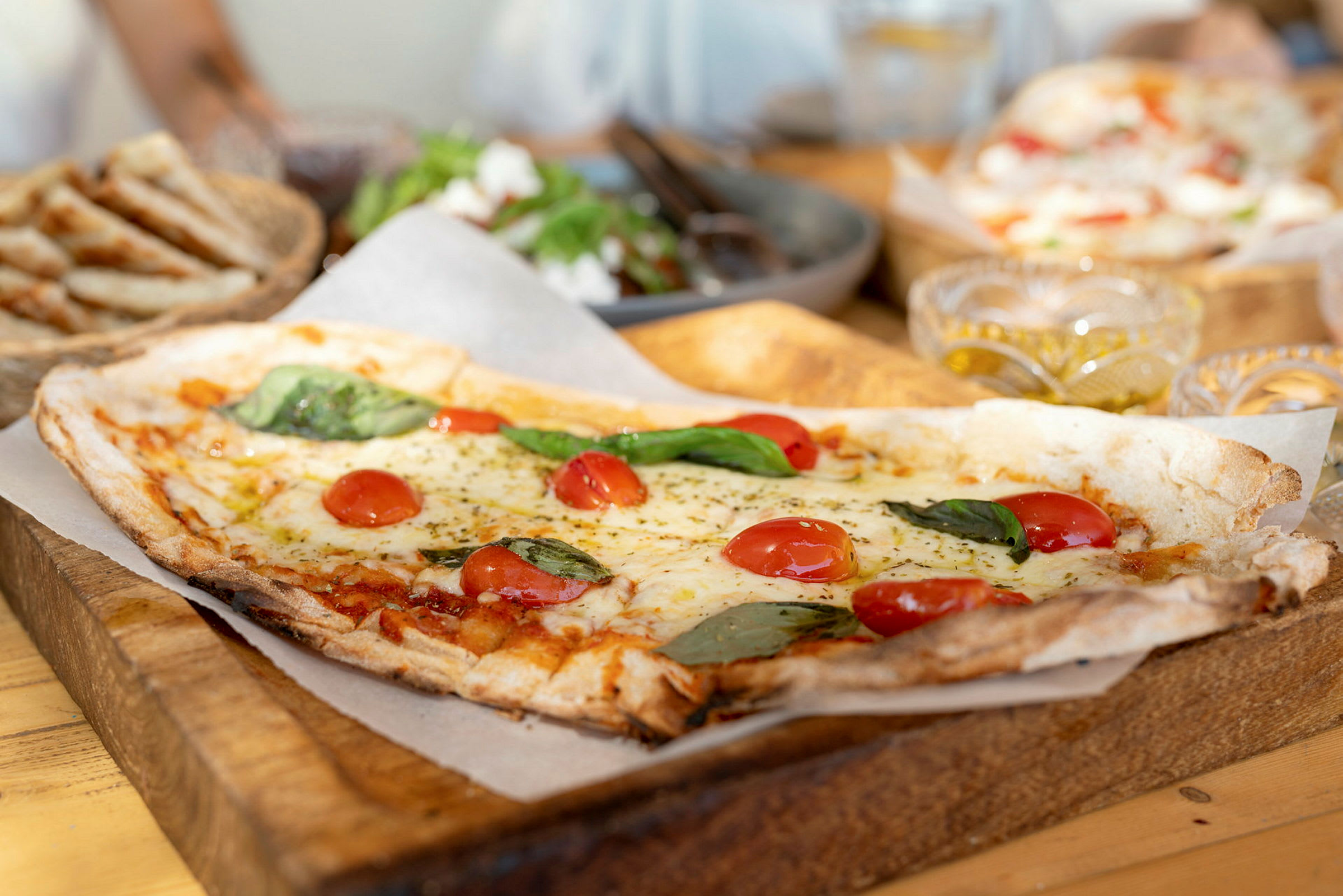 Firkantet pizza med tomater og basilikum på skjærebrett av tre. (AI-generert tekst)
