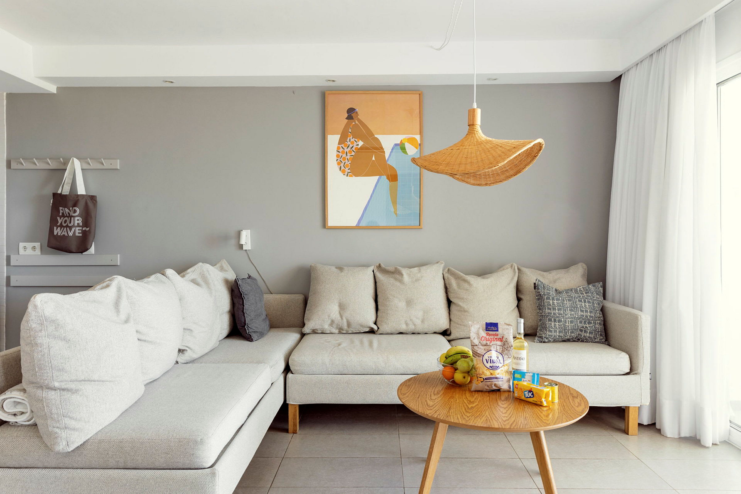 Bilde av en moderne stue med en grå vegg, grå sofa og et trebord med snacks og drikke. (AI-generert tekst)