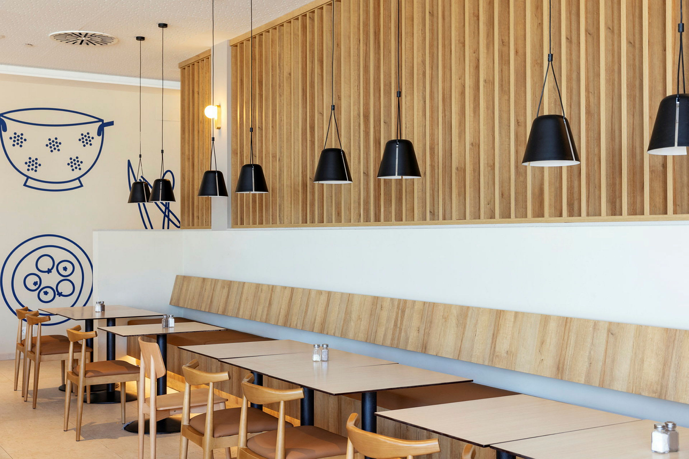 En moderne restaurant med trefinerpanel og svarte hengelamper. (AI-generert tekst)
