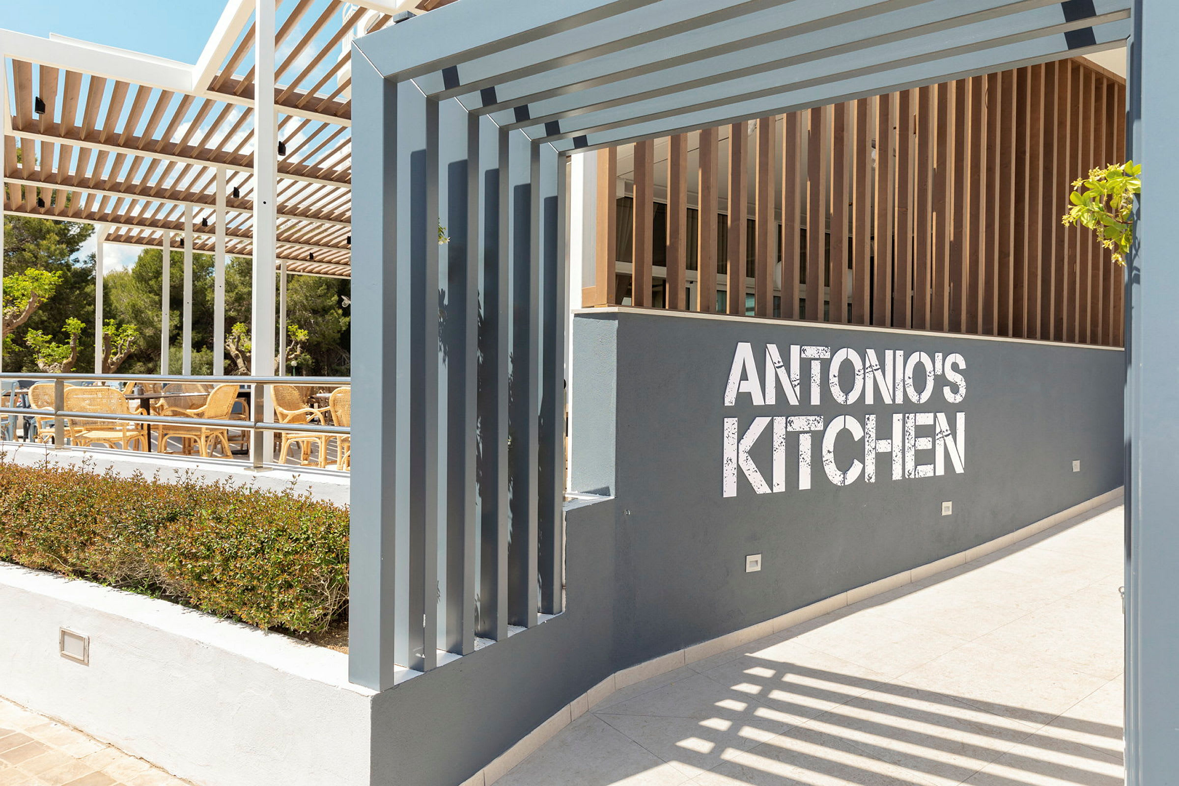 Inngang til restaurant Antonio's Kitchen med sitteplasser utendørs. (AI-generert tekst)