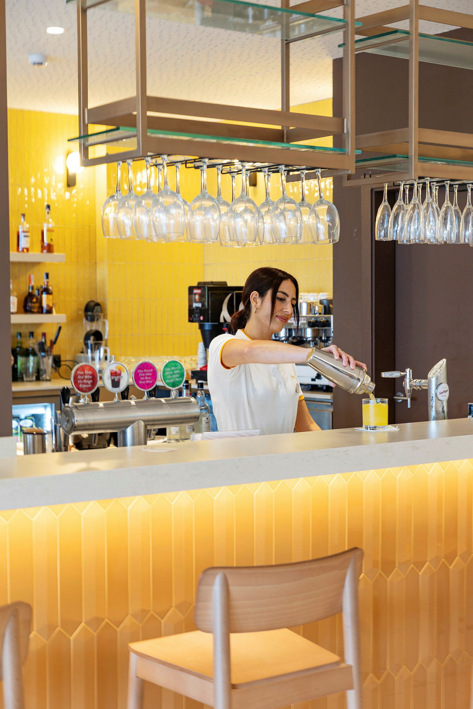 Person forbereder en drink ved en bar med gul innredning. (AI-generert tekst)
