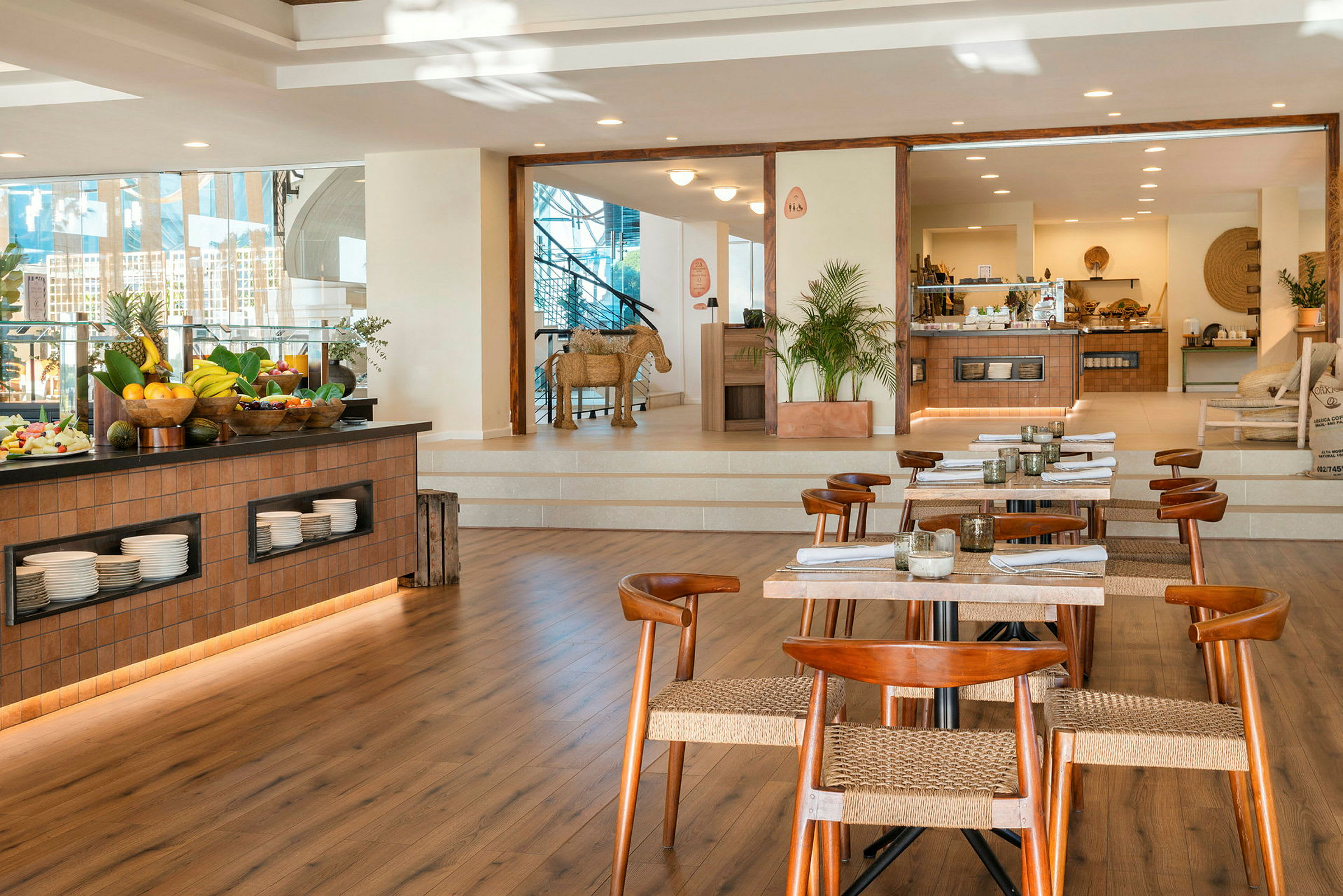 En restaurant med trebord og stoler samt en buffet med frukt og serveringsskåler. (AI-generert tekst)