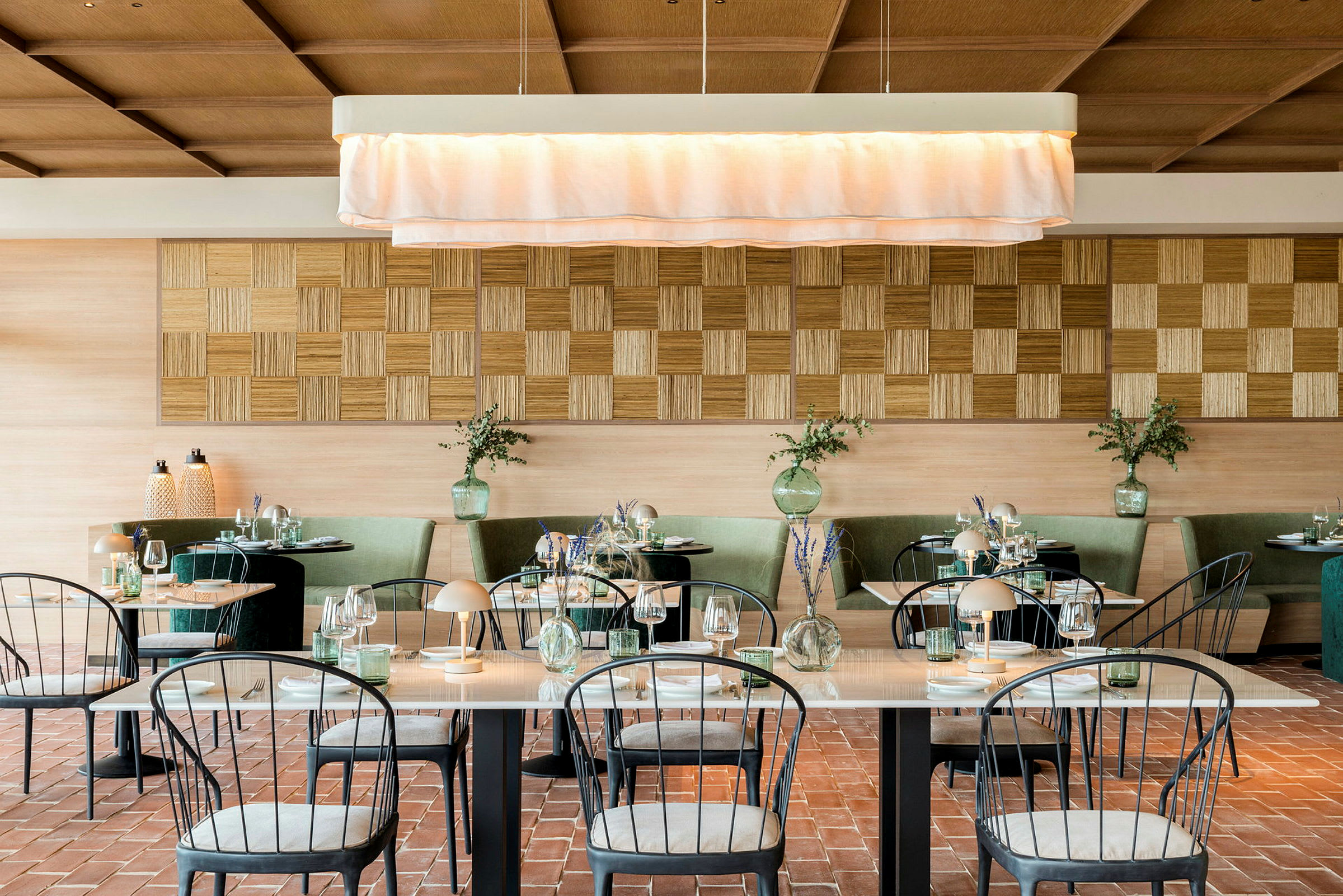 En elegant restaurant med pent dekkede bord, grønne sofaer og et lyst interiør. (AI-generert tekst)