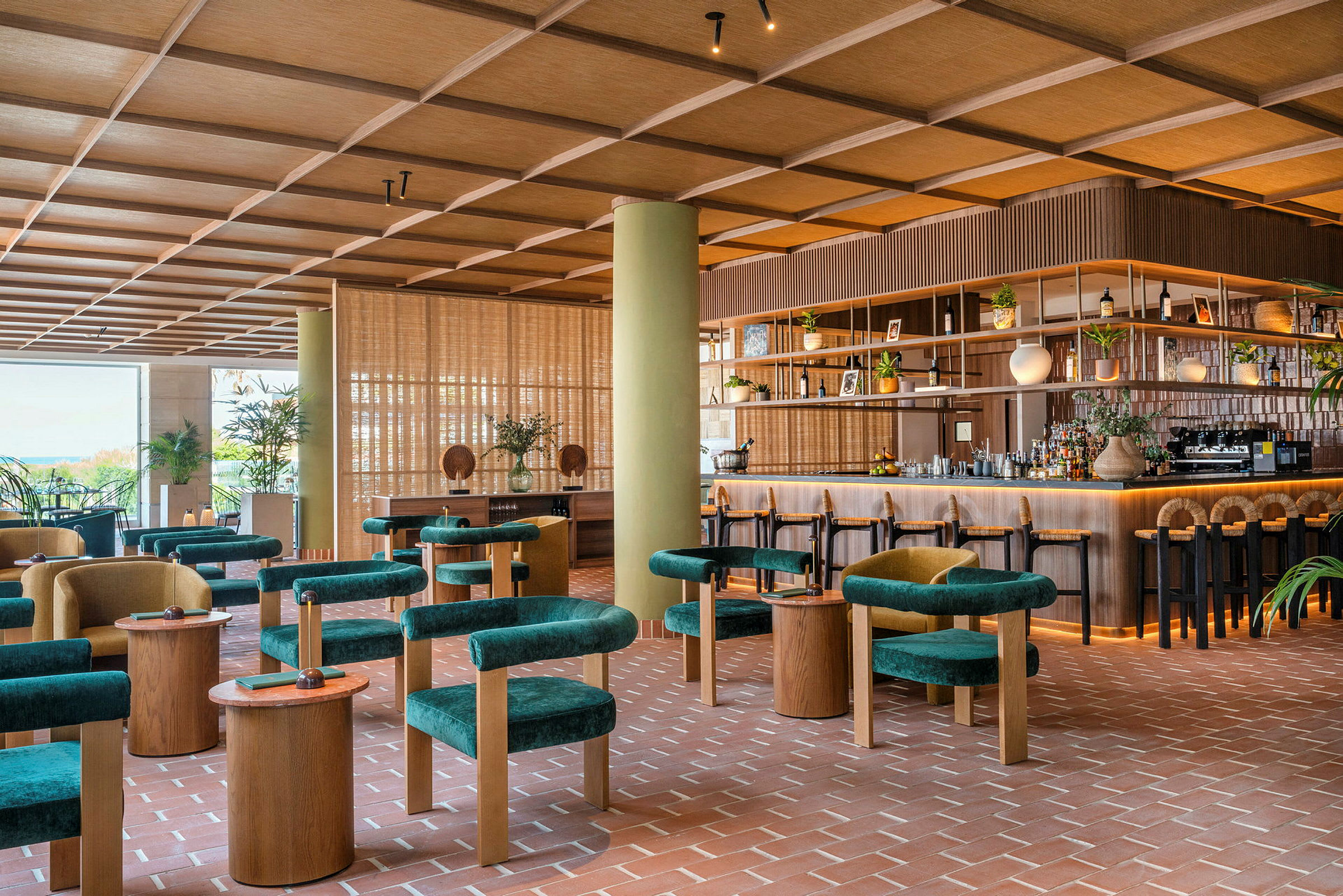 Bilde av en moderne bar eller restaurant med grønne sittemøbler, trebord og en velorganisert bardisk. Interiøret har en varm og innbydende følelse. (AI-generert tekst)