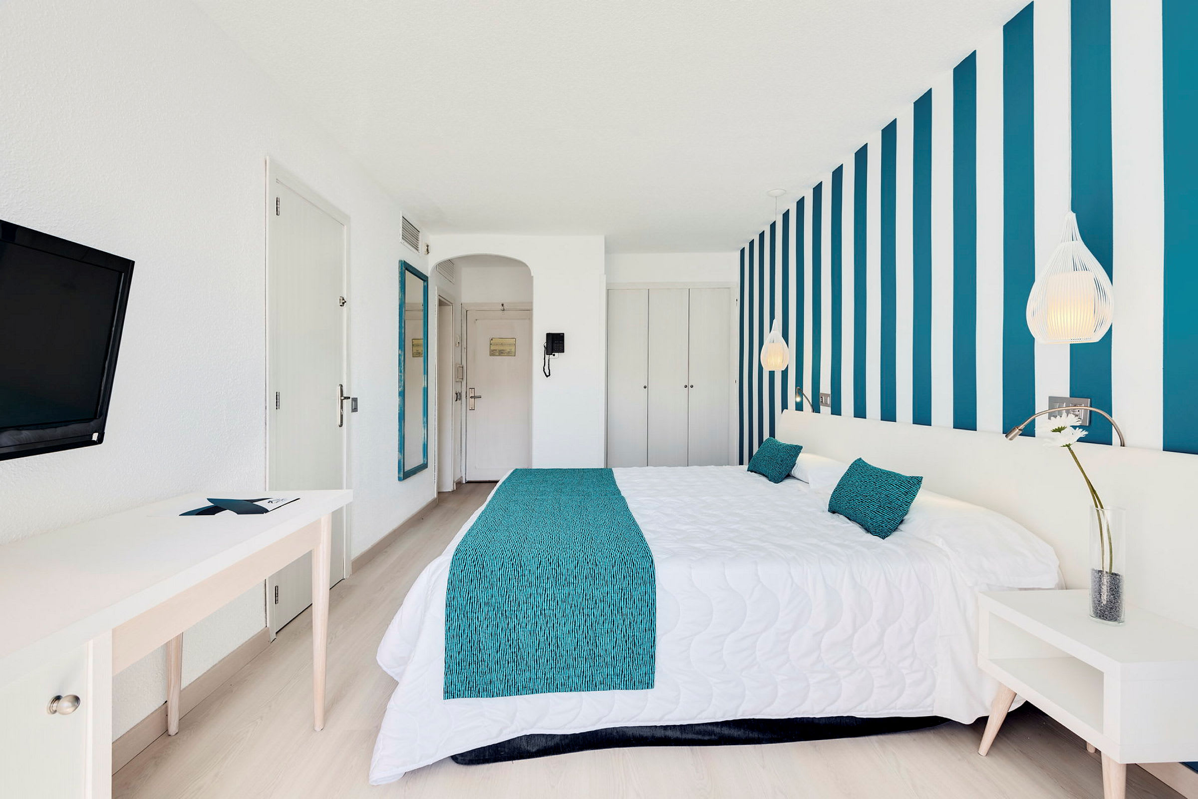 Et hotellrom med blå og hvite dekorative detaljer og en komfortabel dobbeltseng. (AI-generert tekst)