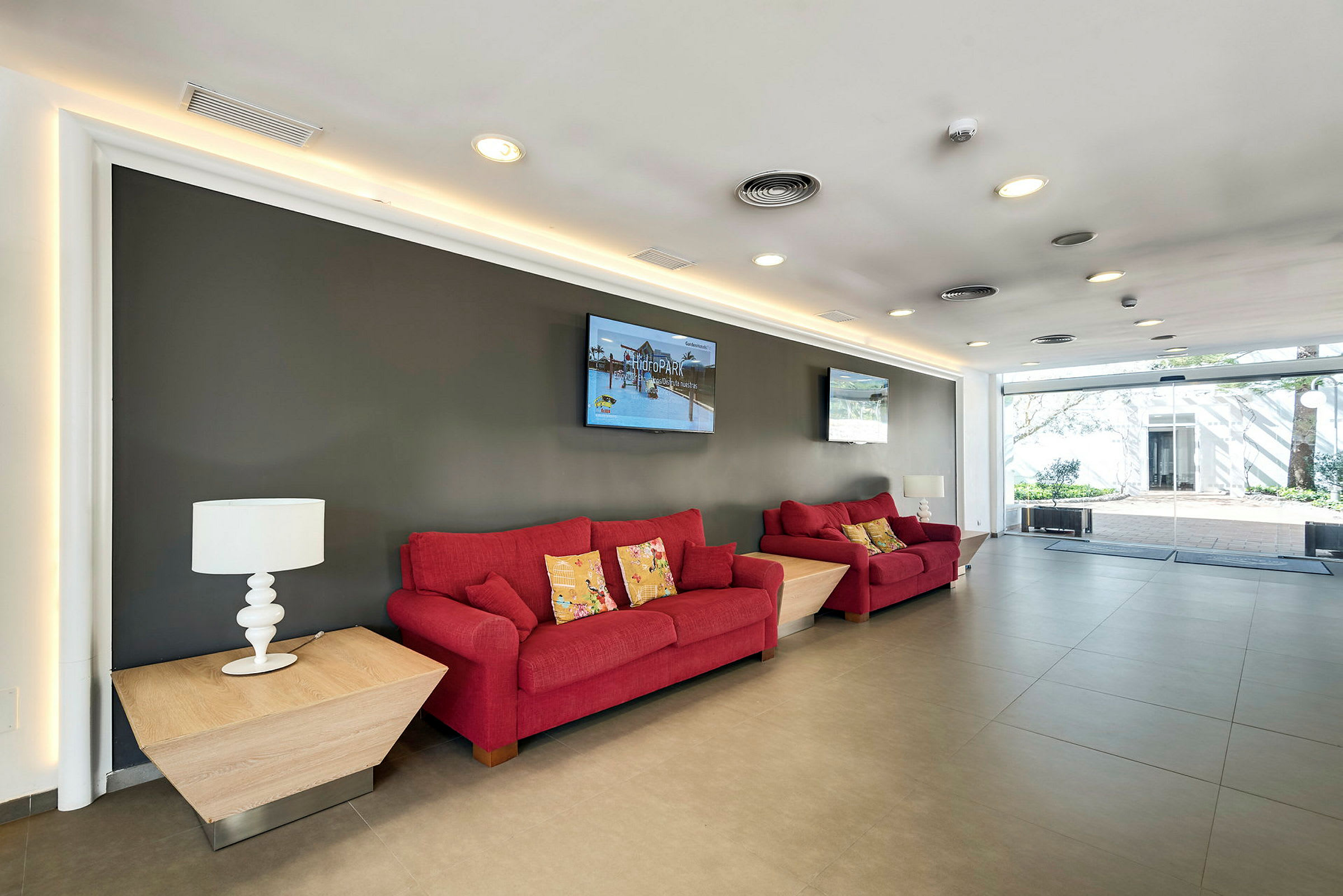Rød sofa og bord i en moderne innredet lounge. (AI-generert tekst)