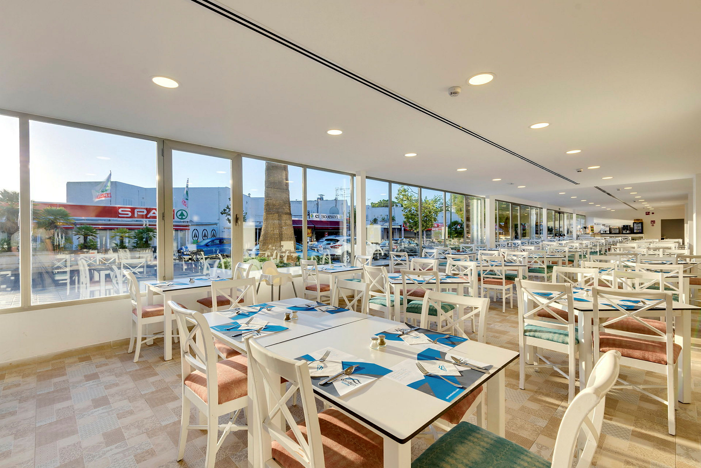 Restaurant med hvite møbler og vinduer mot gaten. (AI-generert tekst)