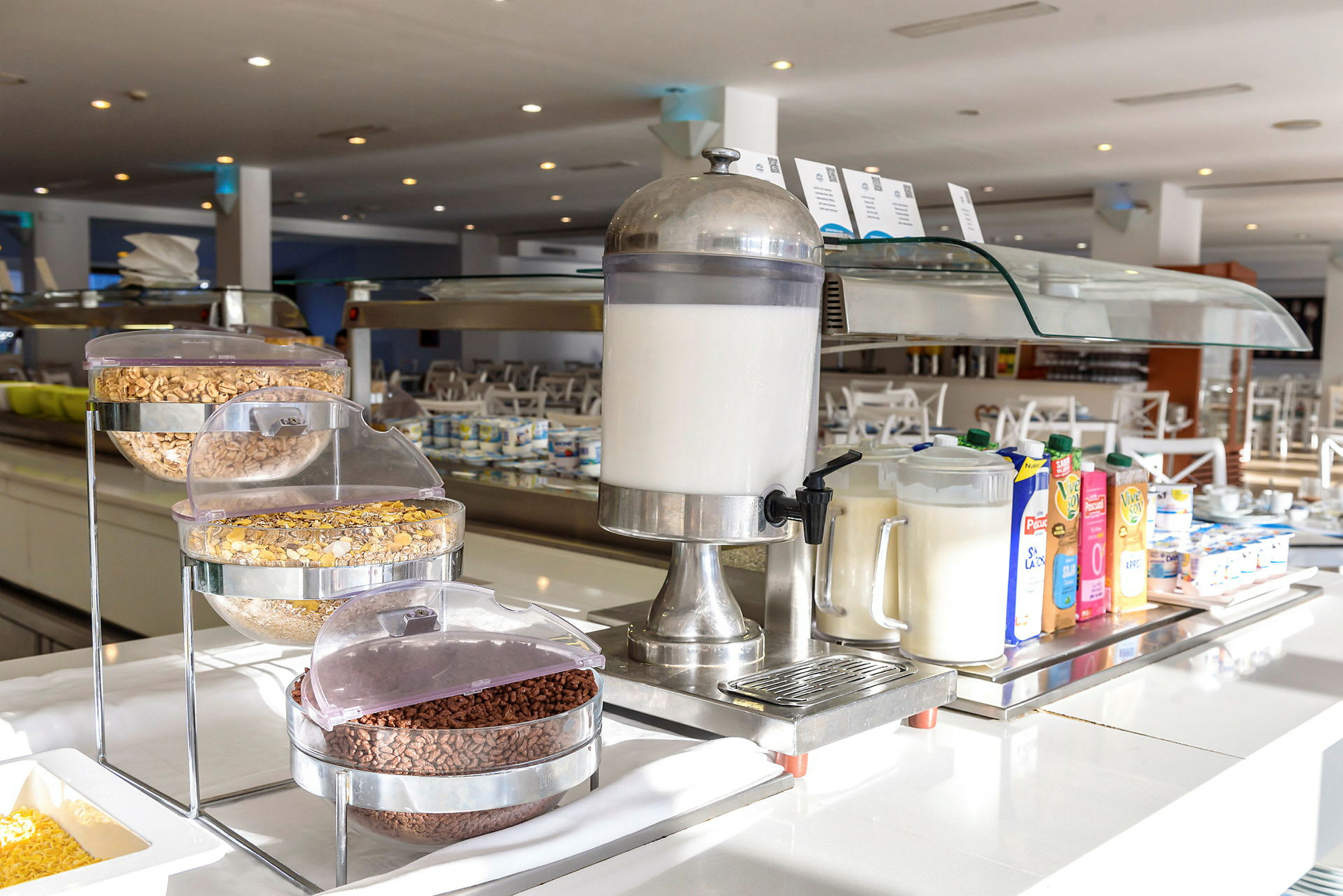 Bilde av en hotellfrokostbuffet med melkautomat, korn og juicekartonger. (AI-generert tekst)