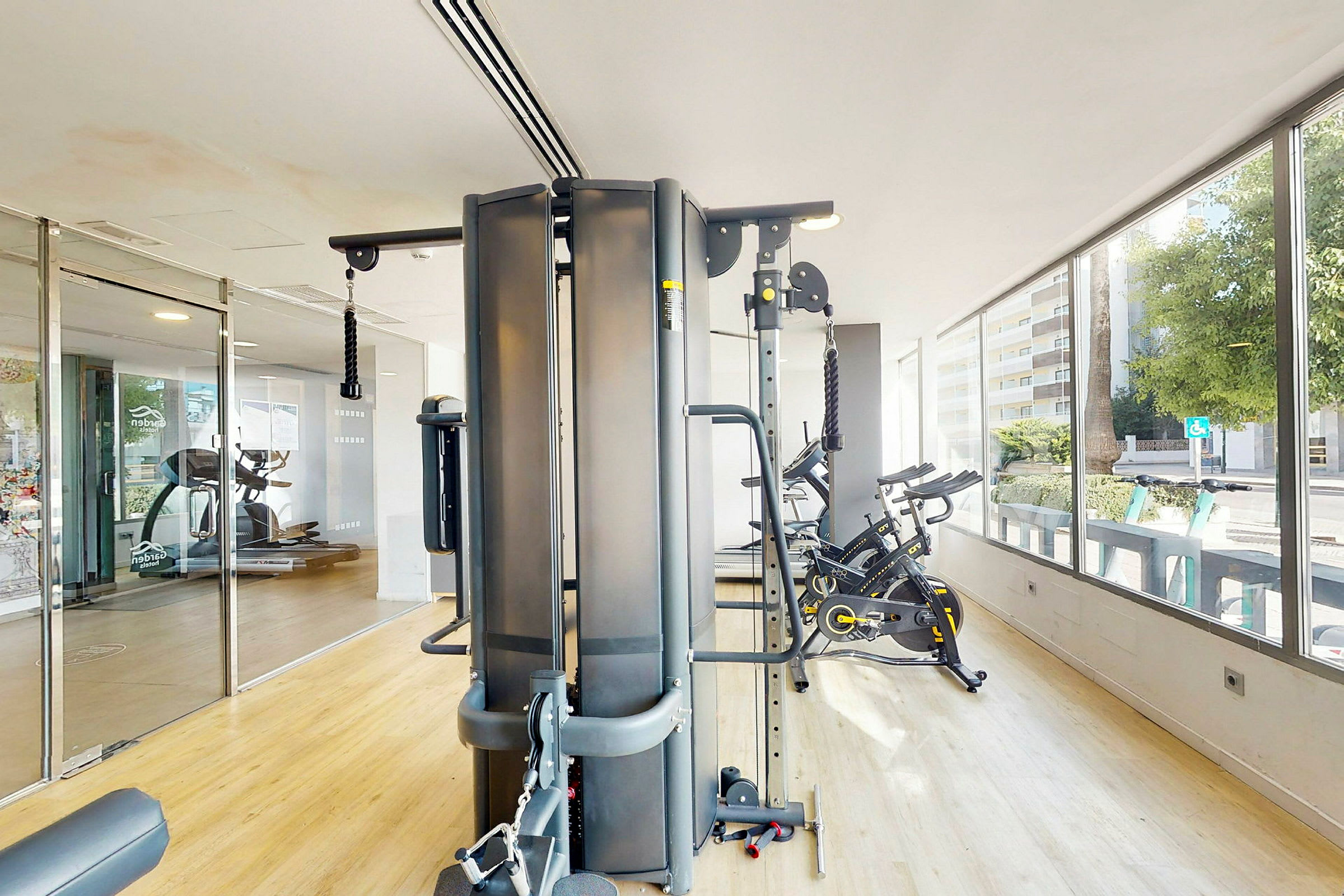 Et treningsstudio med ulike treningsapparater, inkludert ergometersykler og en multi-gymmaskin. (AI-generert tekst)