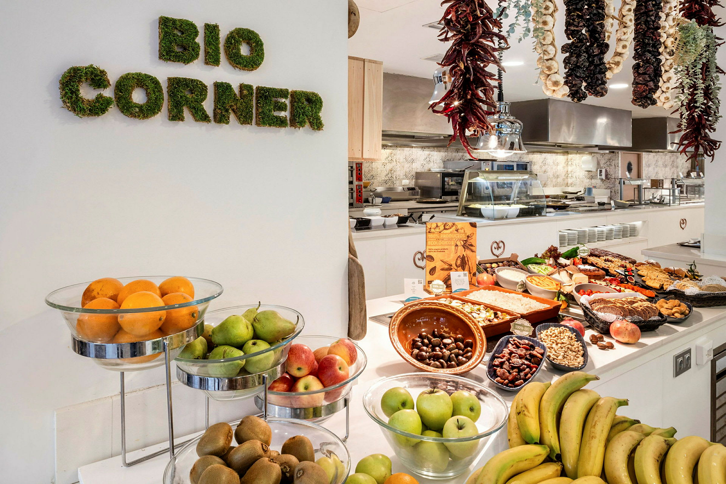Frukt og matvarer på et bord i et kjøkkenområde med skiltet 'Bio Corner'. (AI-generert tekst)