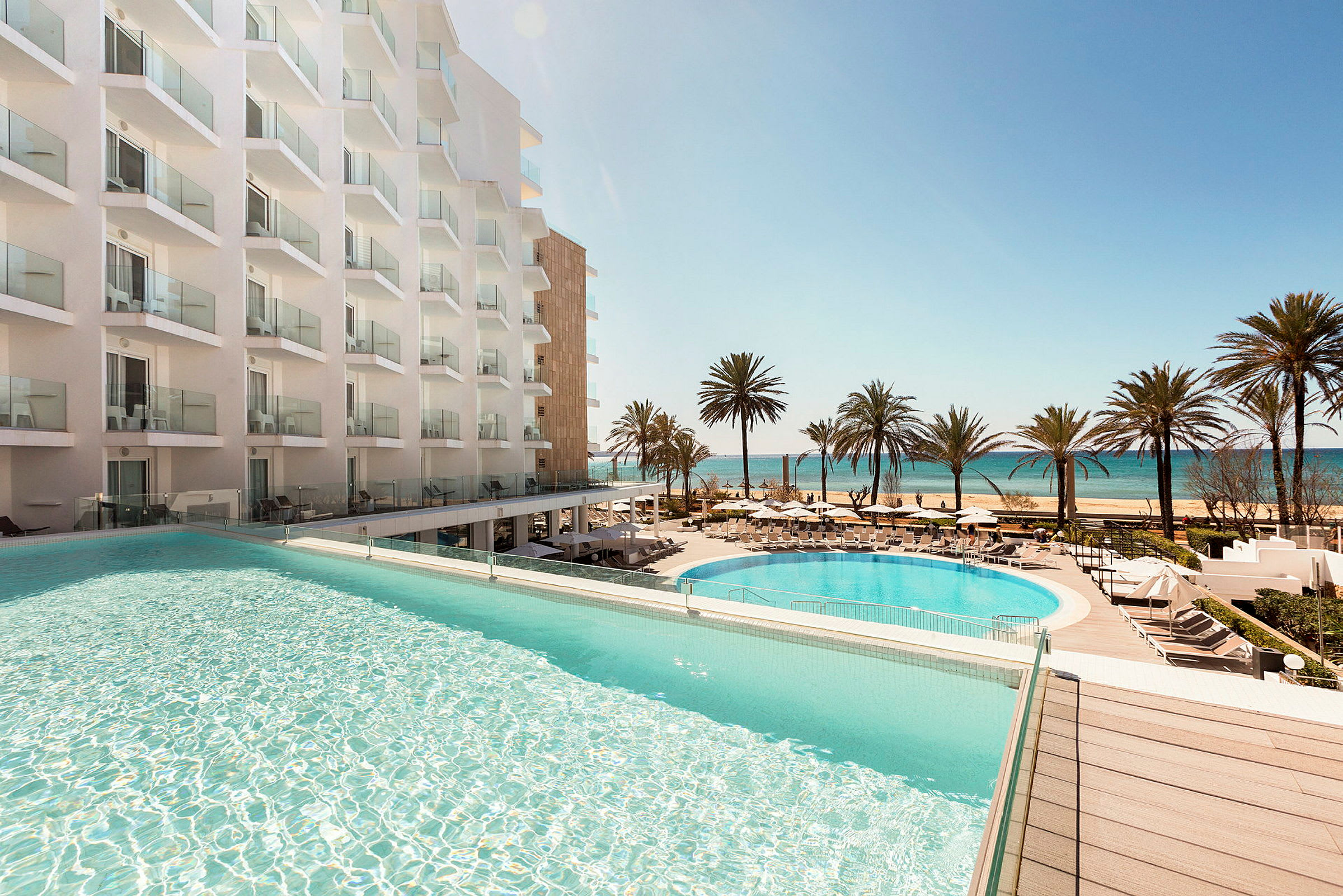 Hotell med basseng og utsikt over stranden og havet. (AI-generert tekst)