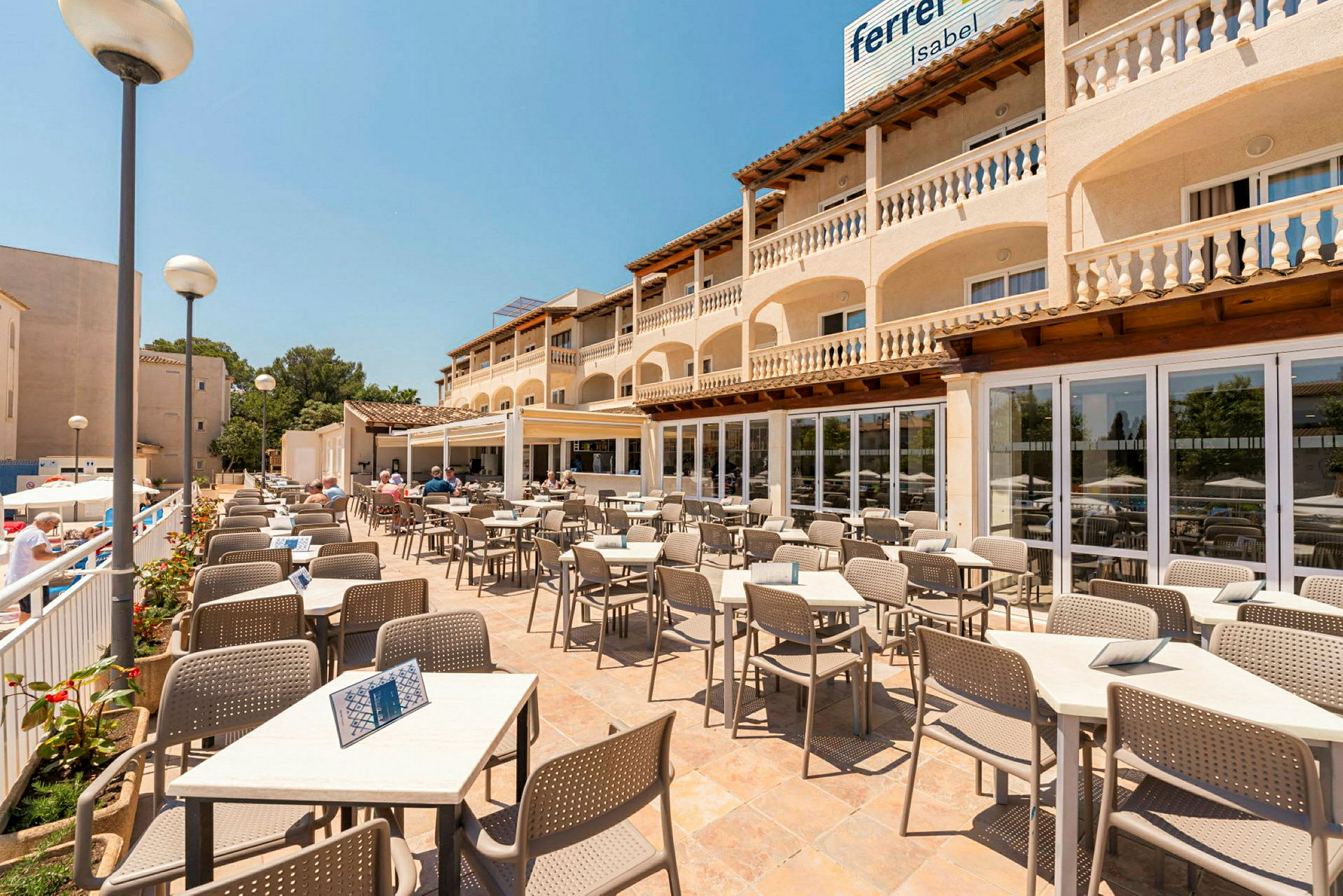 Terrasserestaurant med bord og stoler, omgitt av en bygning med balkonger. (AI-generert tekst)