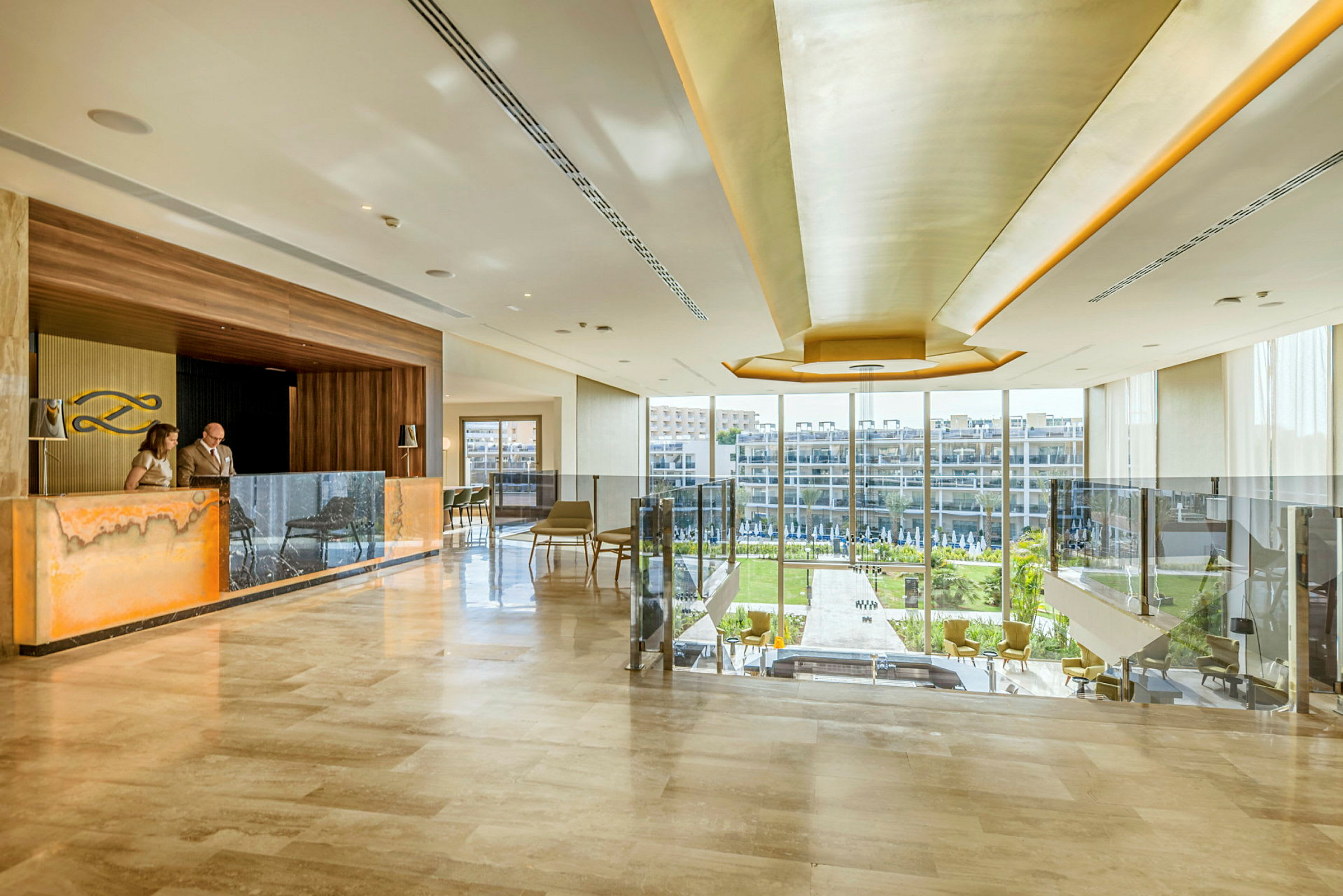 Elegant hotellobby med resepsjon og store vinduer som vender ut mot en frodig utsikt. (AI-generert tekst)