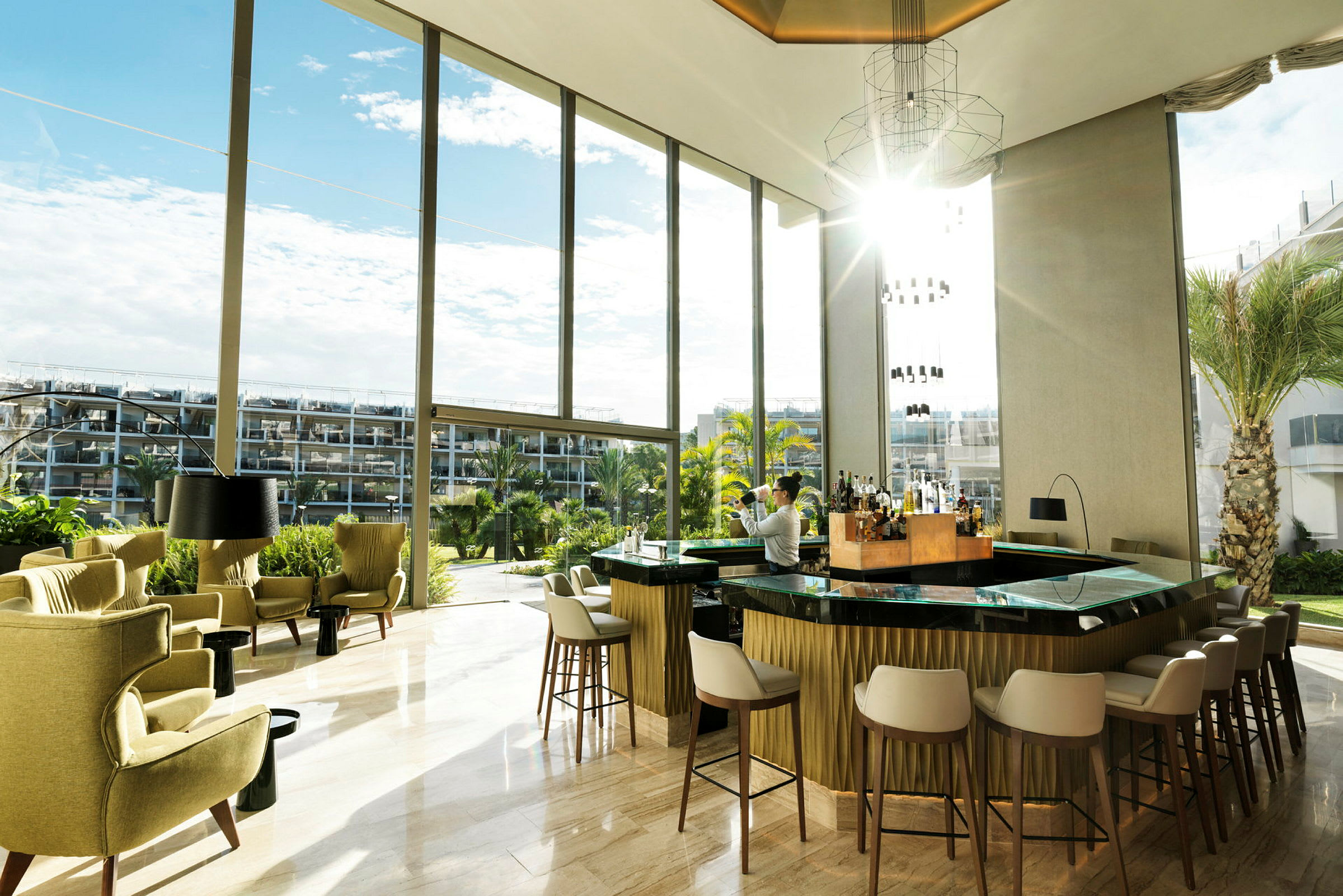 En elegant hotellbar med store vinduer og utsikt over en hage. (AI-generert tekst)