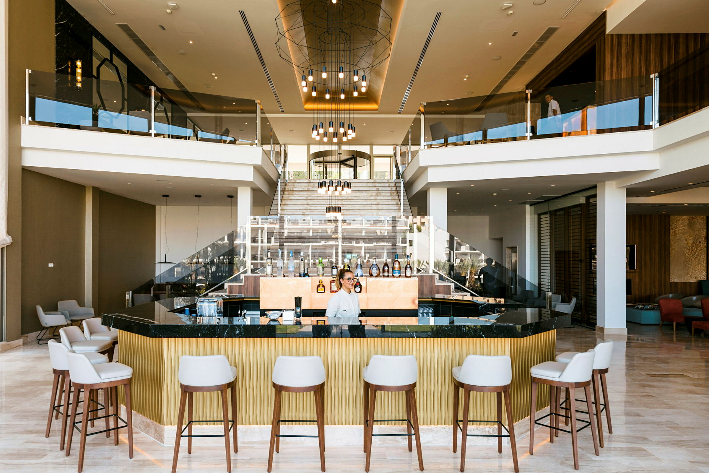 Et hotellobby med en moderne bar, sitteplasser og en sentral trapp. (AI-generert tekst)