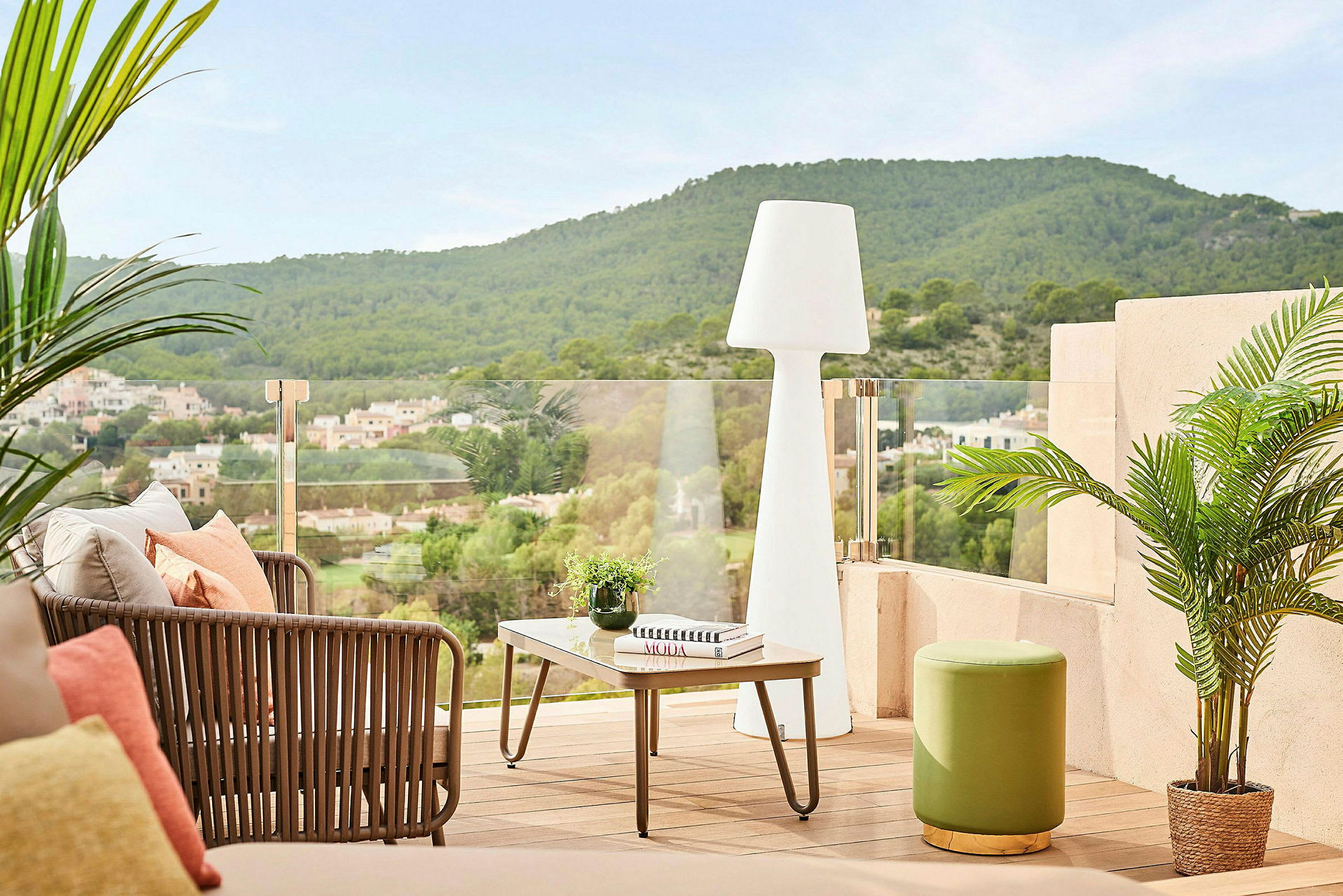 En terrasse med sittemøbler, bord, plante og utsikt over fjell og hus. (AI-generert tekst)