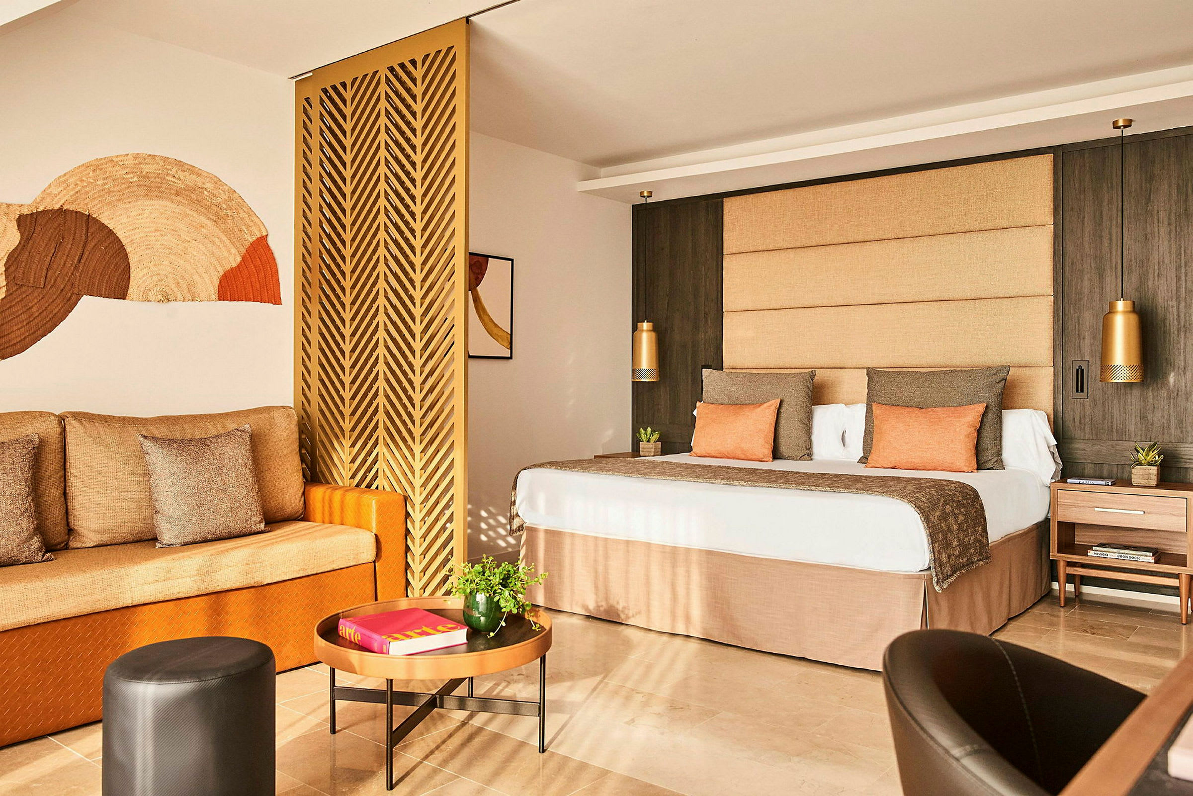 Et komfortabelt hotellrom med en sofa, et bord og en stor seng med dekorative puter og sengegavl. (AI-generert tekst)