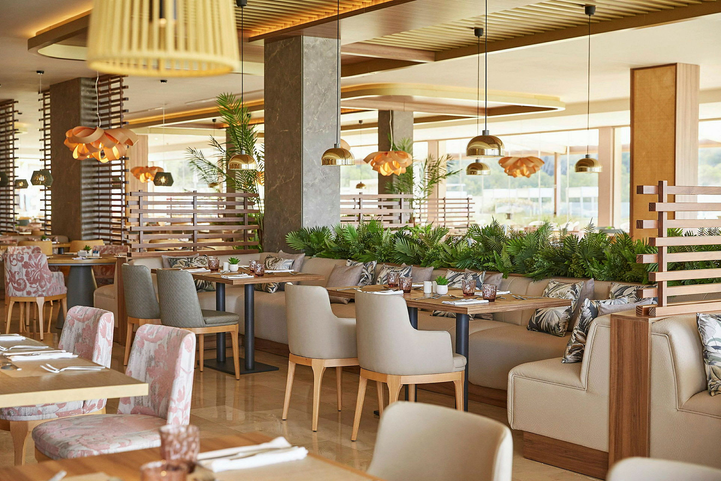 Et moderne og elegant innredet restaurantområde med bord og stoler, dekorert med planter og belysningsdetaljer. (AI-generert tekst)