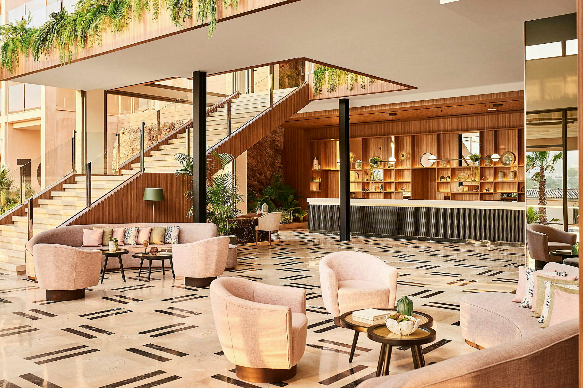 En hotellobby med sofaer og lenestoler, en resepsjonsdisk og trapp omgitt av planteinnredning. (AI-generert tekst)