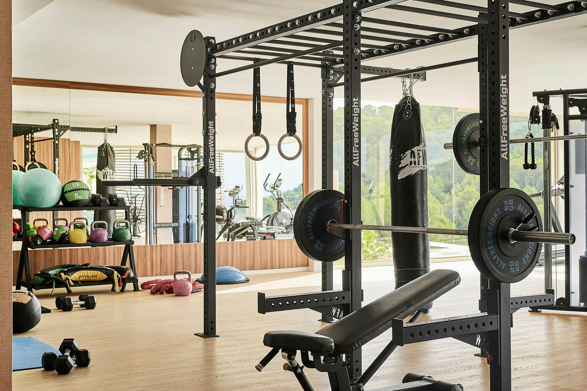 Et treningsstudio med treningsutstyr, inkludert vekter, kettlebells, ringer og en boksesekk. (AI-generert tekst)