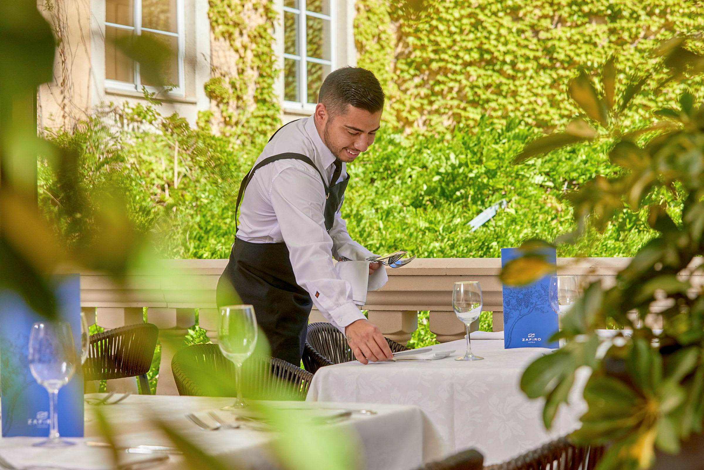 En servitør ordner et bord på en uterestaurant. (AI-generert tekst)