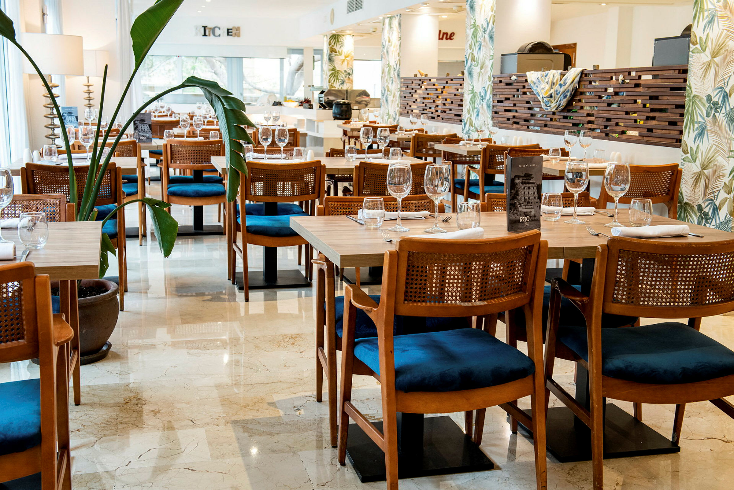 En restaurant med dekkede bord og stoler samt planter i potter. (AI-generert tekst)