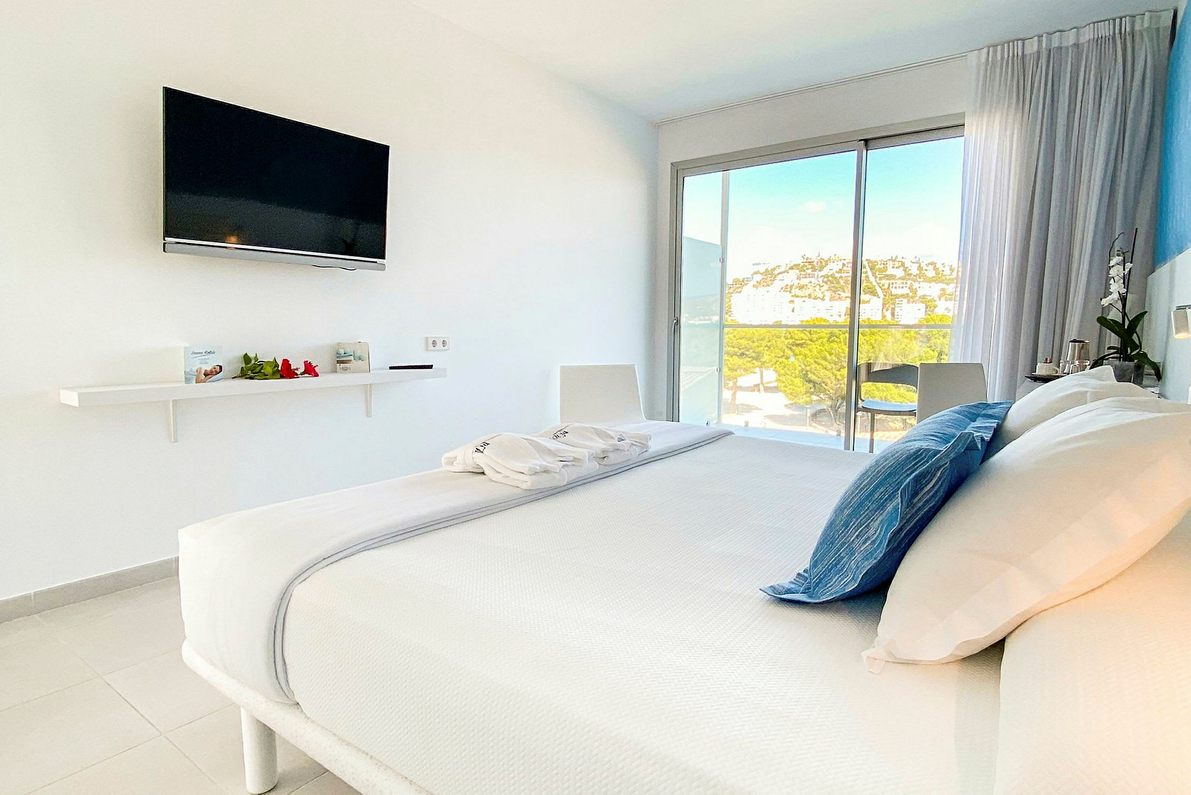 Et moderne hotellrom med en dobbeltseng og en TV på veggen. Rommet har store vinduer med utsikt over landskapet. (AI-generert tekst)