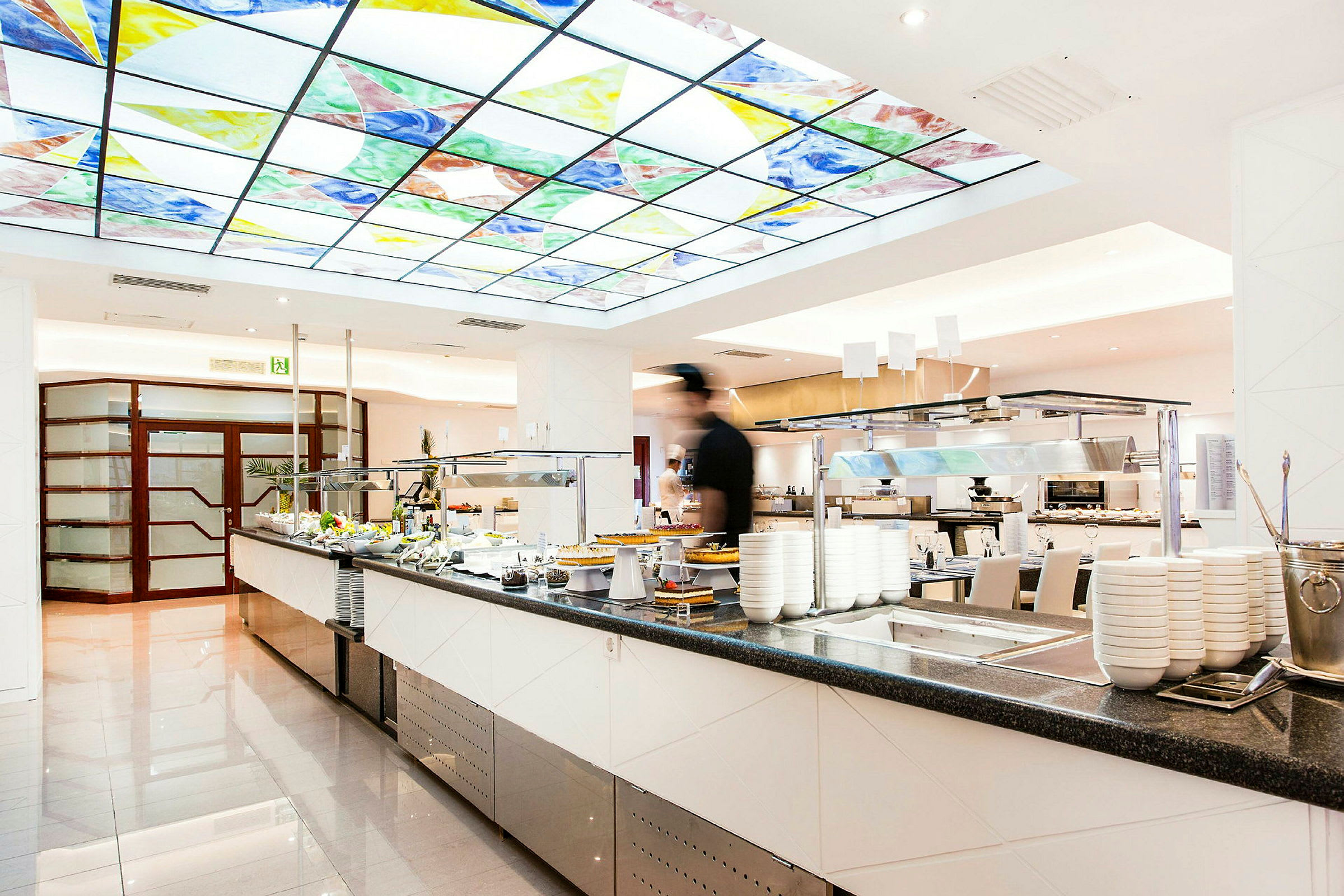 En matservering med buffet og et takpanel med farget glass. (AI-generert tekst)