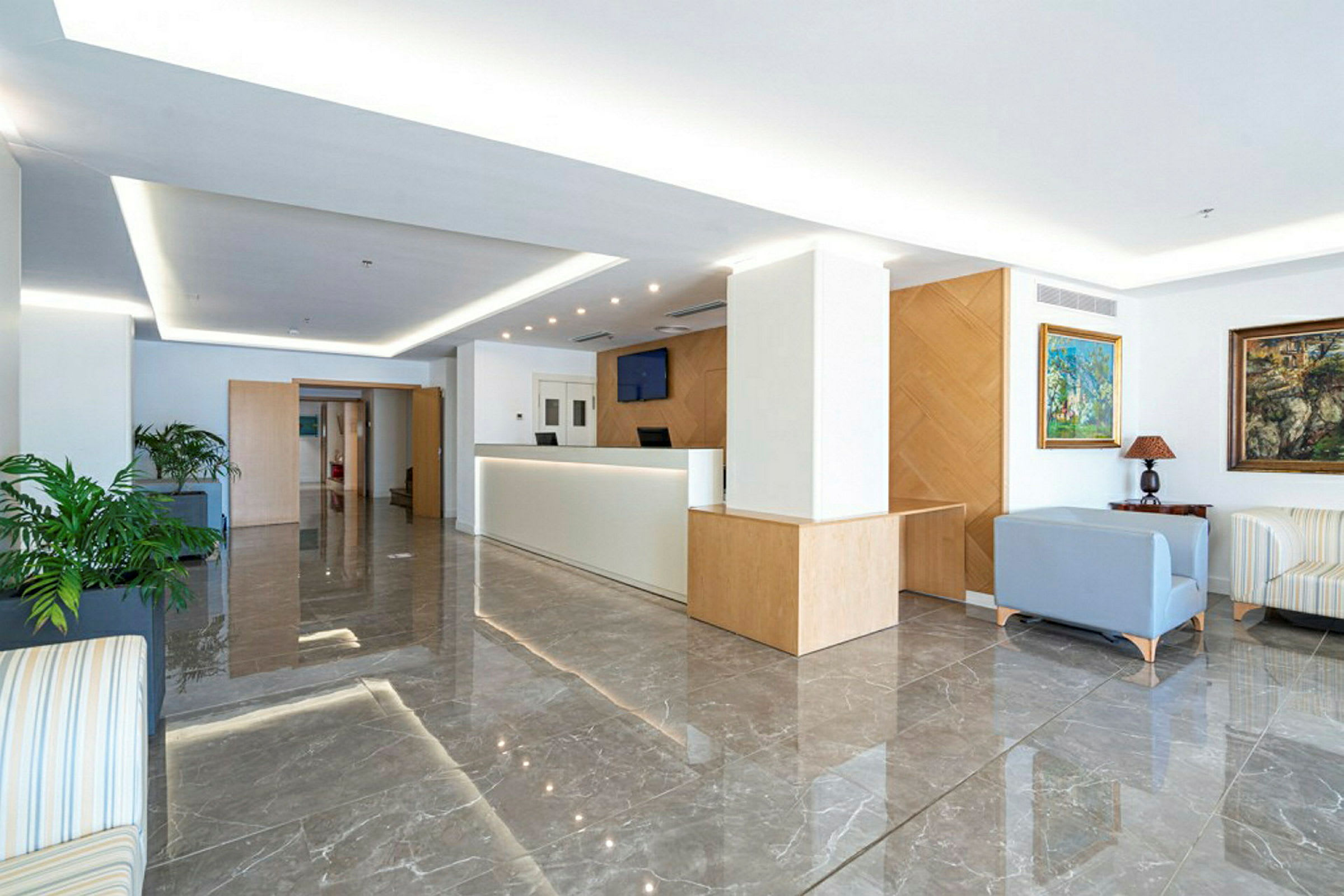 Et moderne og lyst hotellområde med resepsjon og sittegruppe. (AI-generert tekst)