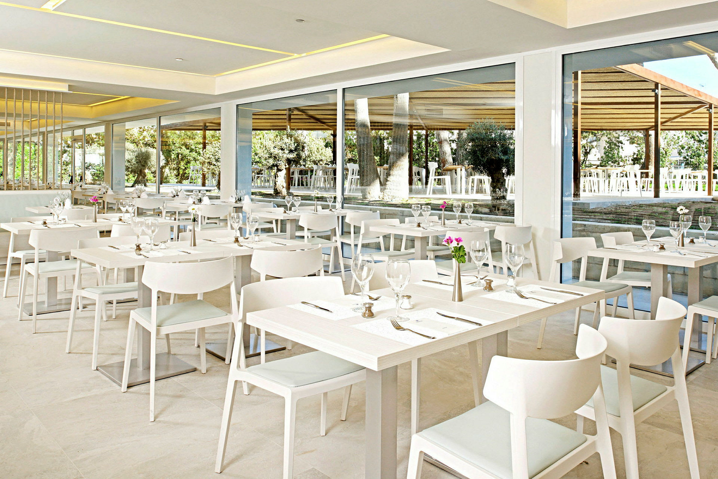 En moderne restaurant med hvite møbler og borddekking. (AI-generert tekst)