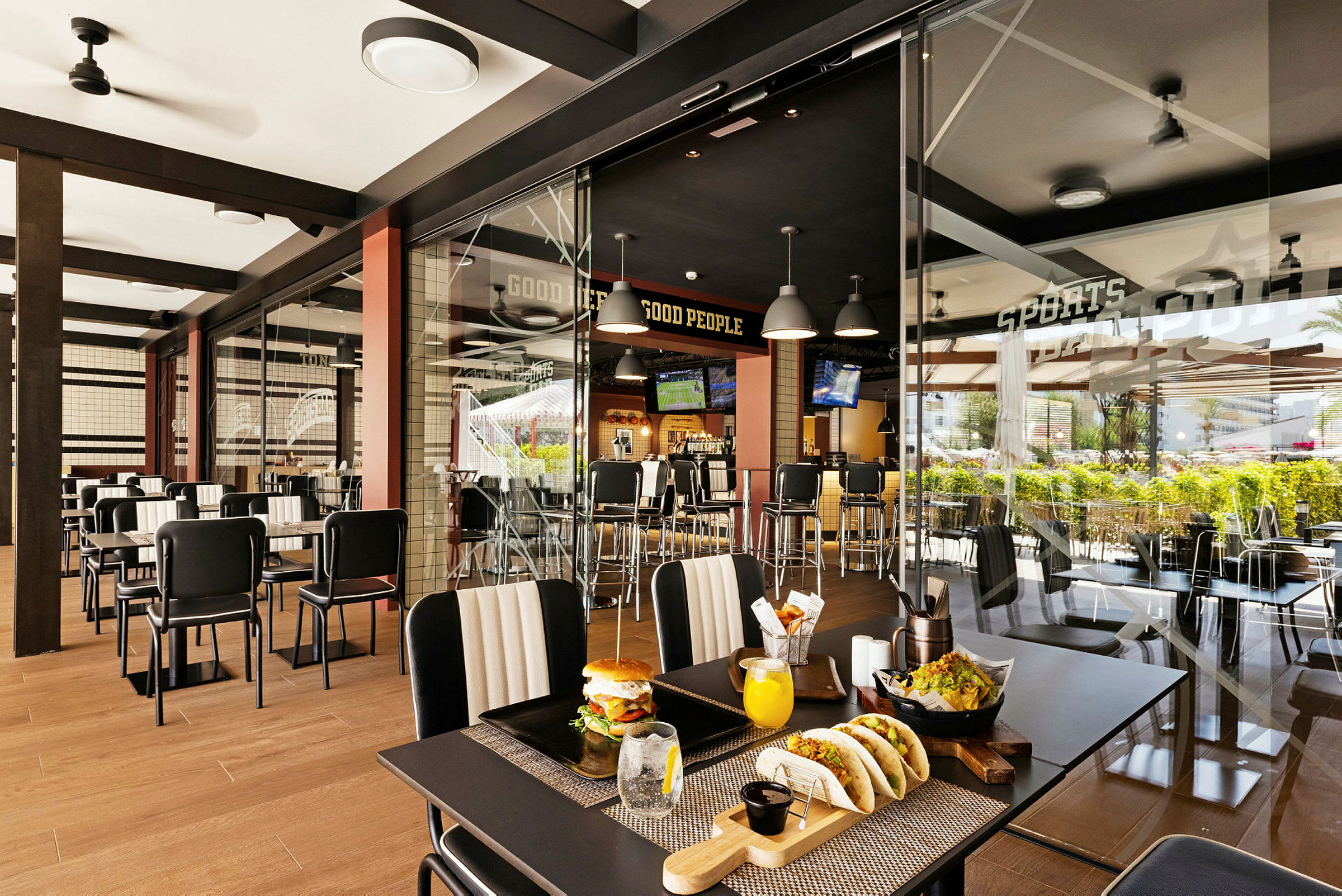 En moderne restaurant med glassvegg, bordplasseringer og synlige matretter. (AI-generert tekst)