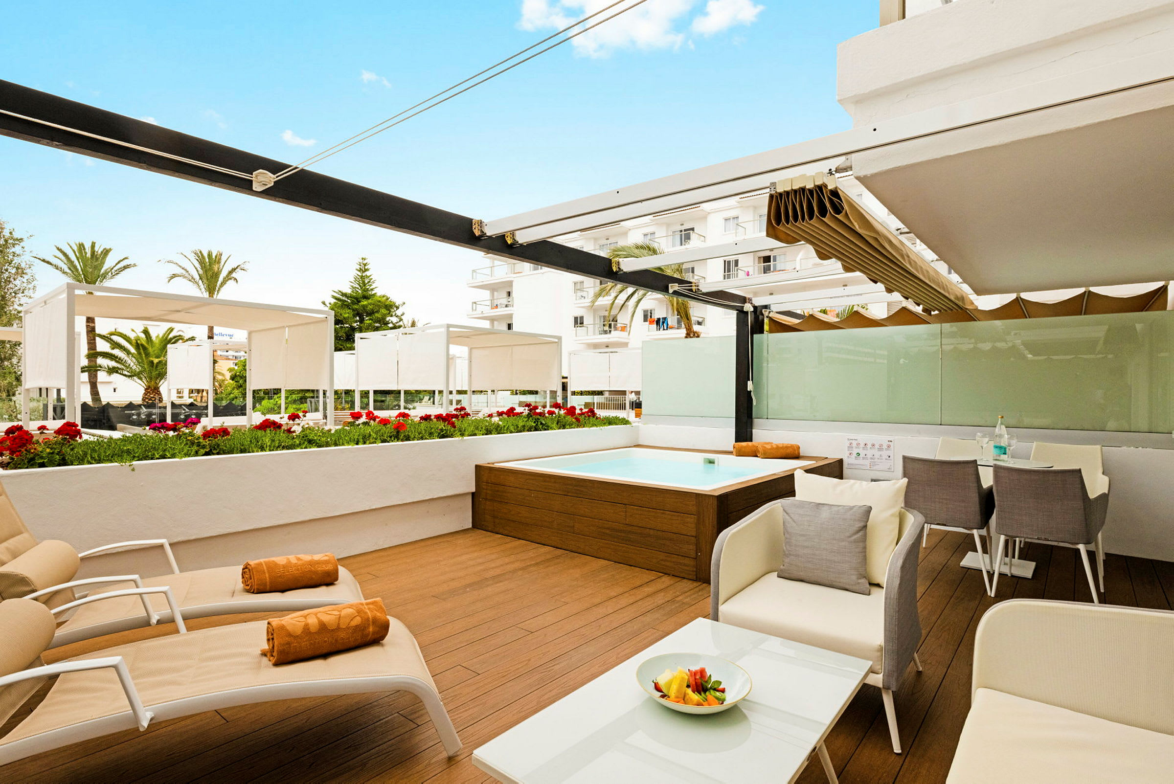 Bilde av en terrasse med solsenger, spisebord og et lite basseng, omgitt av blomster og skyggefulle tak. (AI-generert tekst)