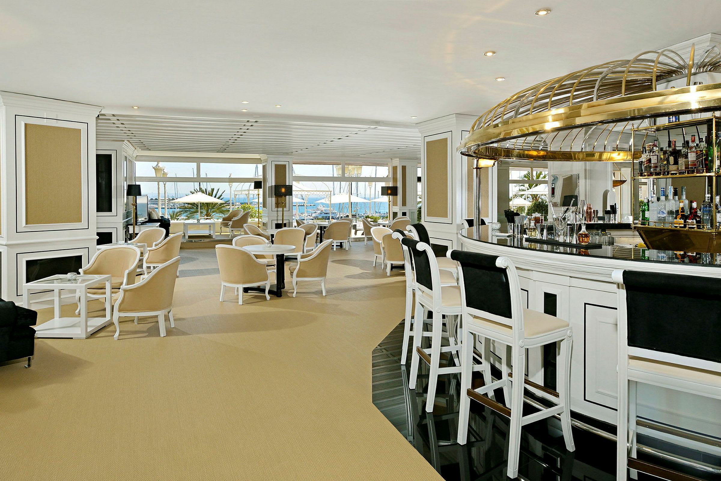 Interiør av en elegant hotellbar med lyse møbler og store vinduer som vender mot havet. (AI-generert tekst)