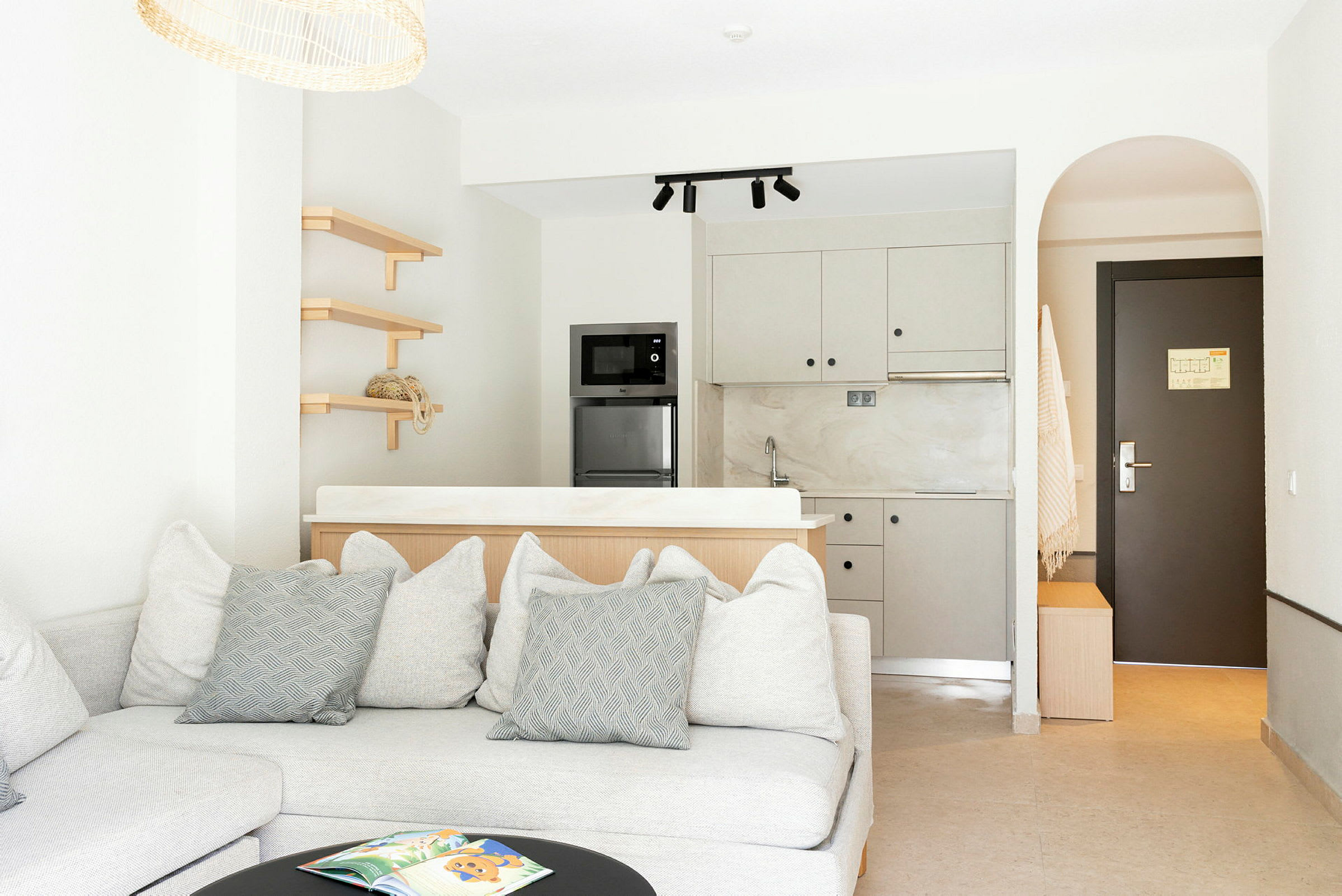 Moderne hotellrom med sofa, kjøkken og dør. (AI-generert tekst)
