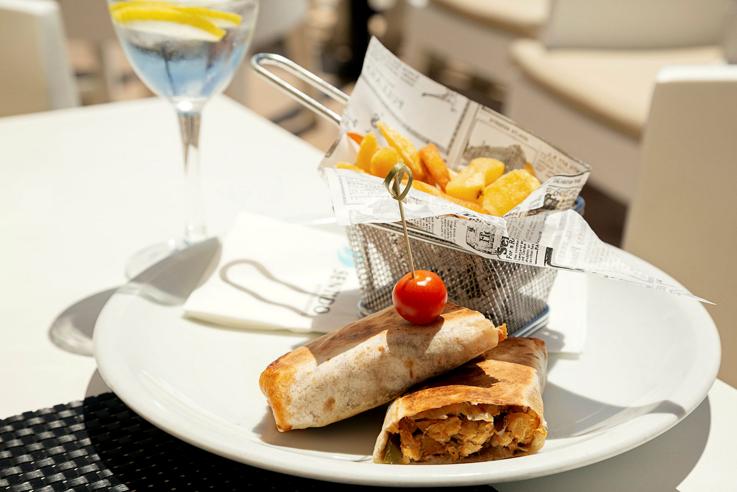 Et måltid med wraps, pommes frites og en glassdrikke. (AI-generert tekst)