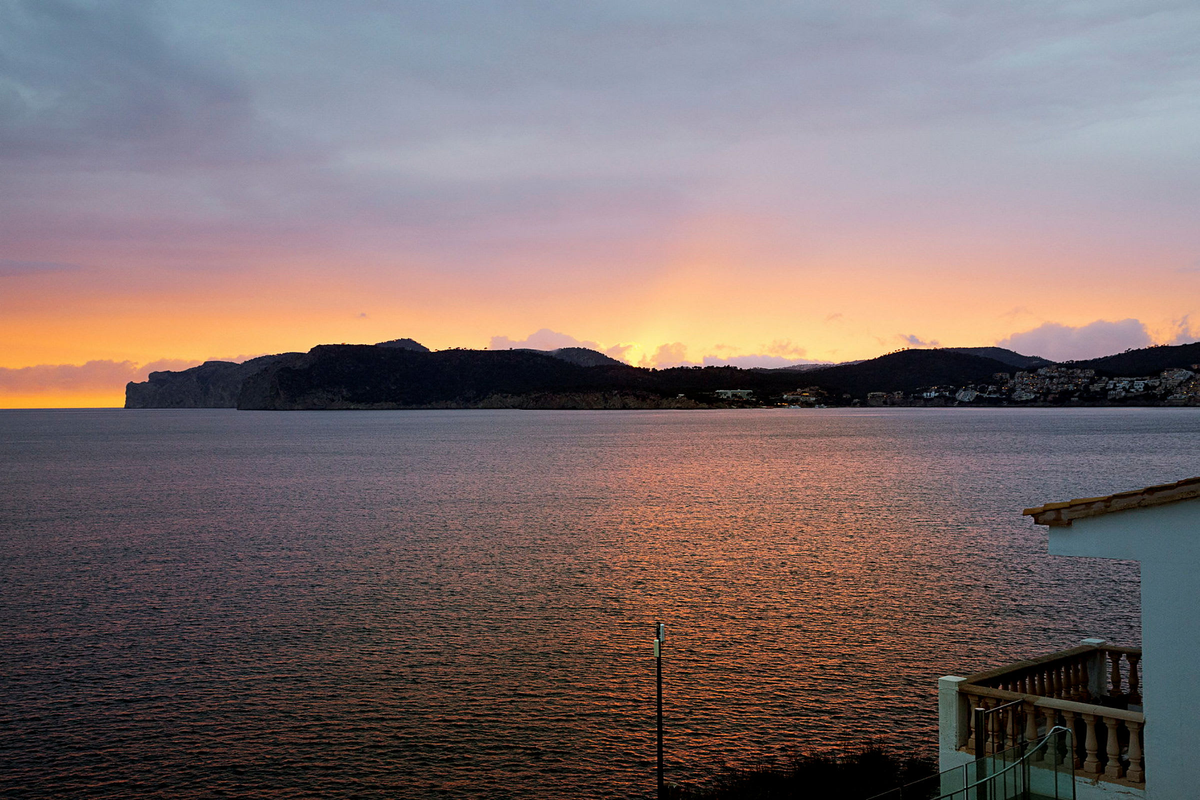Solnedgang over en fjellrik kystlinje ved havet. (AI-generert tekst)