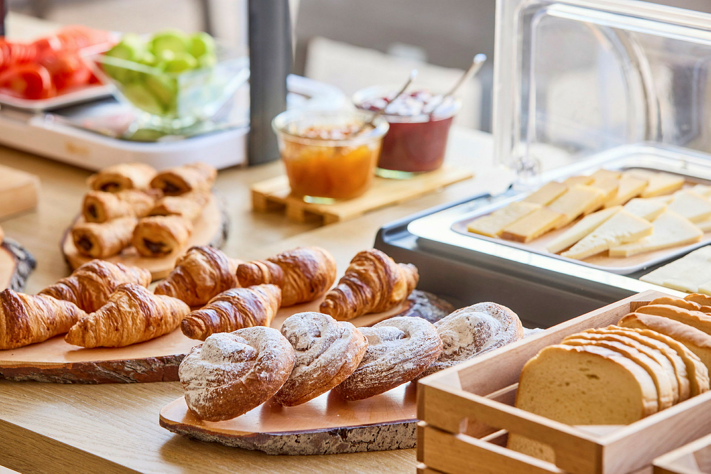 En frokostbuffet med croissanter, brød og skivet ost. (AI-generert tekst)