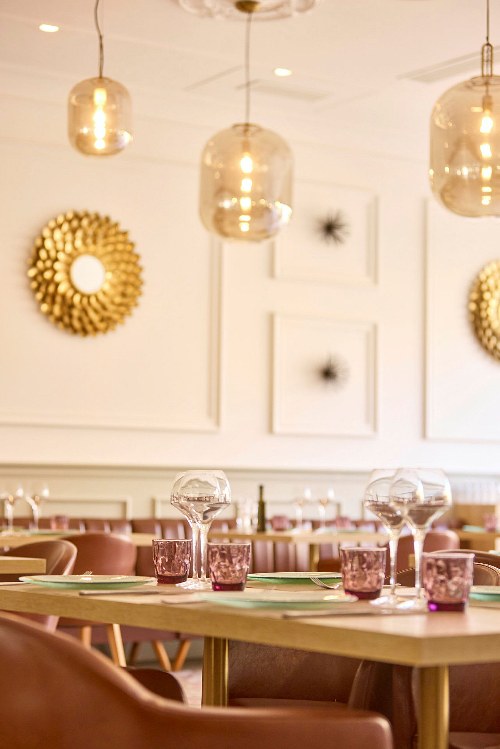 Restaurantbord med glass og tallerkener, omgitt av dekorative lamper og kunstverk. (AI-generert tekst)