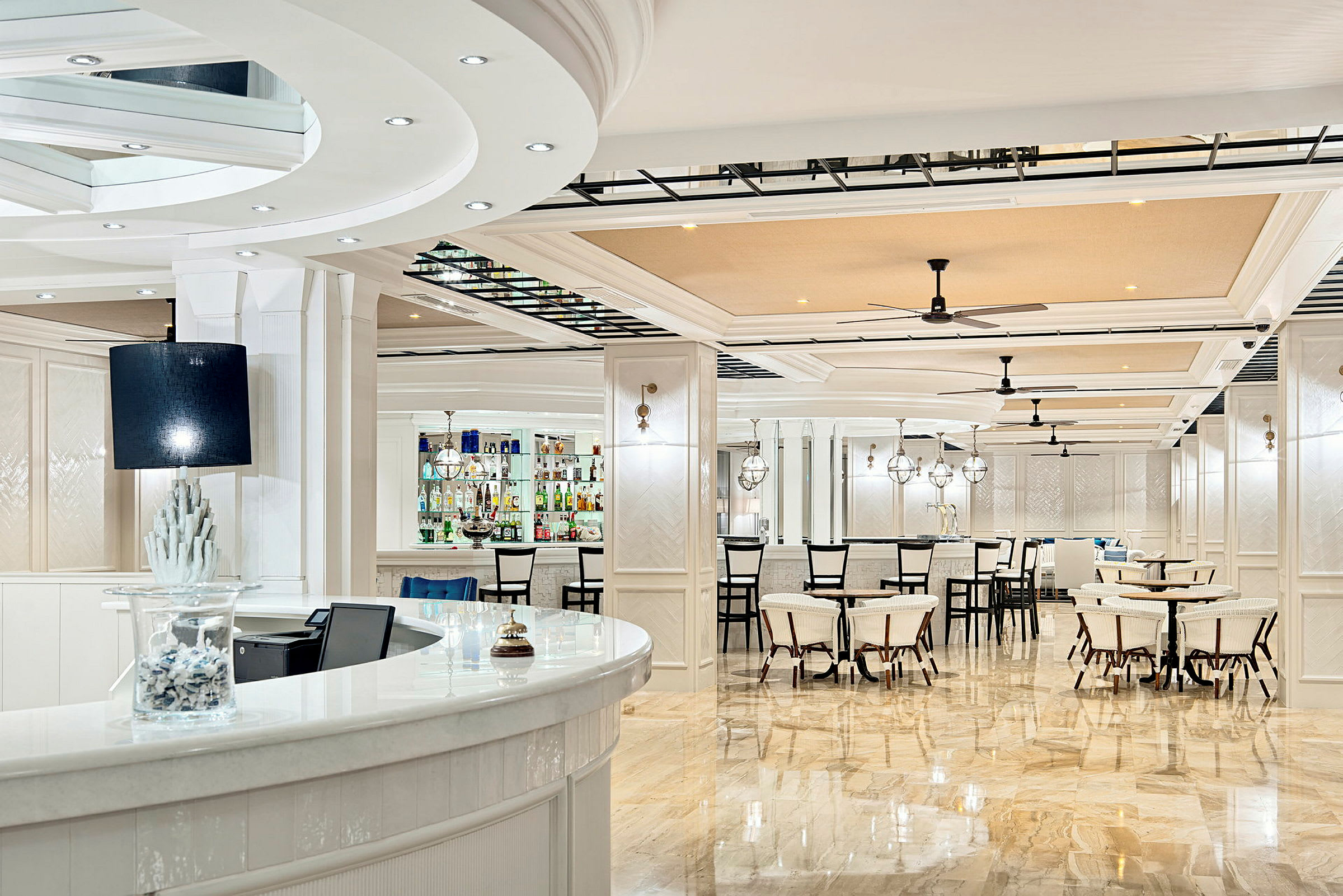 Bildet viser en lys og elegant bar og restaurantmiljø med hvit interiør og speilblanke gulv. (AI-generert tekst)
