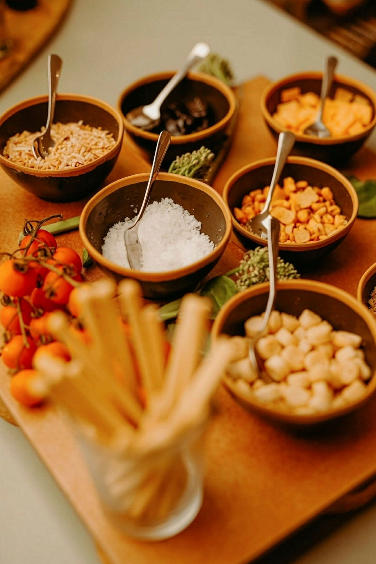 En samling små skåler med forskjellige ingredienser, inkludert tomater og brødpinner. (AI-generert tekst)