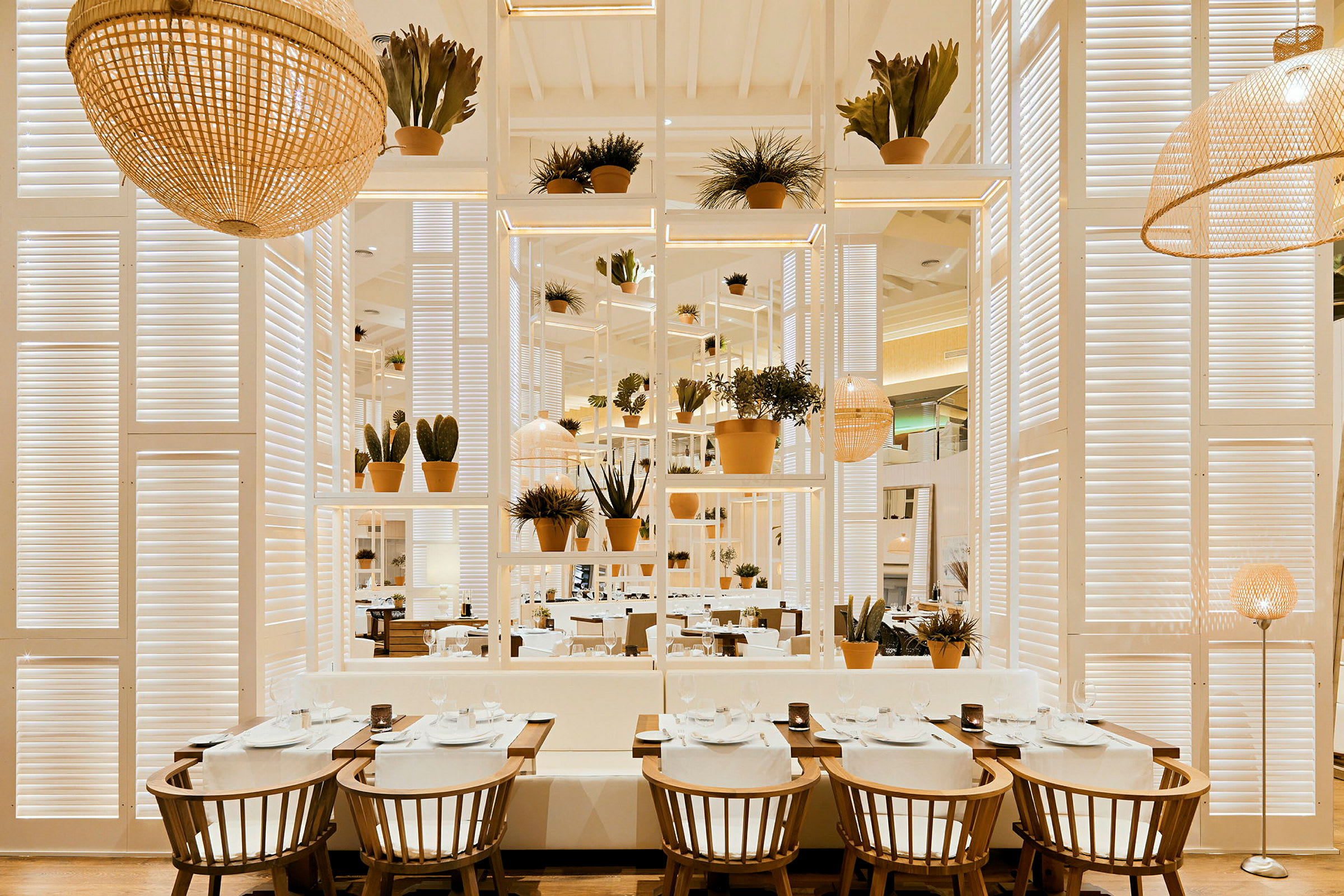 Interiør av en restaurant med bord, stoler og planter i en lys og moderne design. (AI-generert tekst)