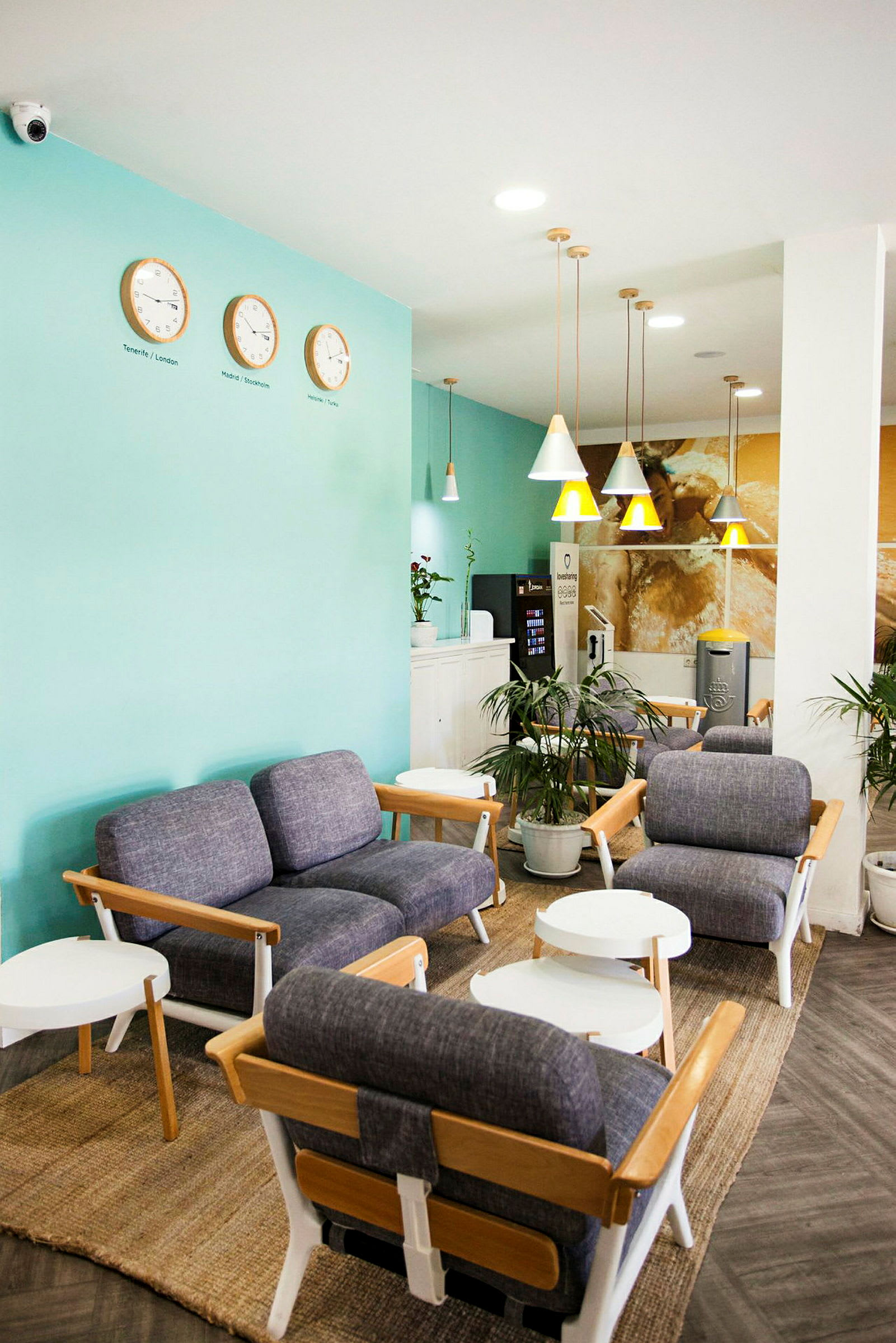 Lounge med blå lenestoler, hvite bord og veggklokker. (AI-generert tekst)